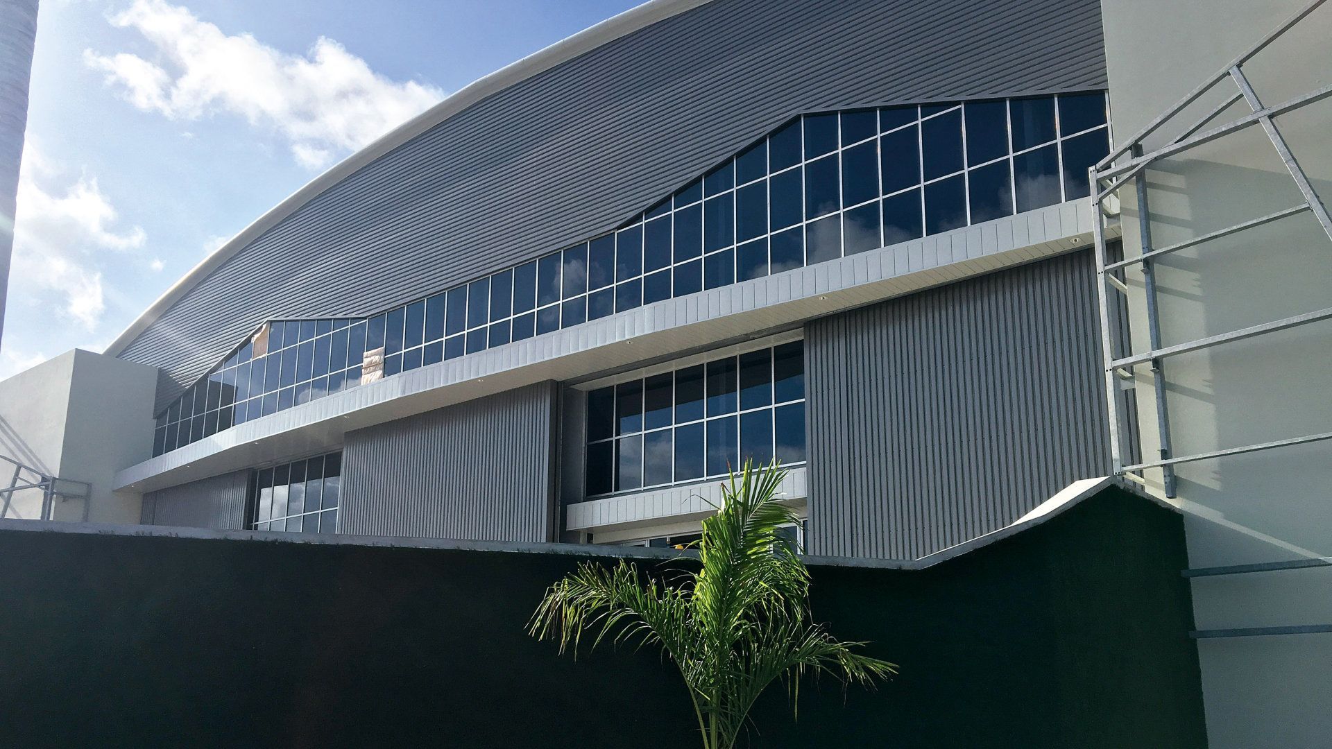 A large building with a lot of windows is behind a fence.