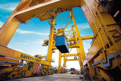 A large yellow crane is lifting a blue container.