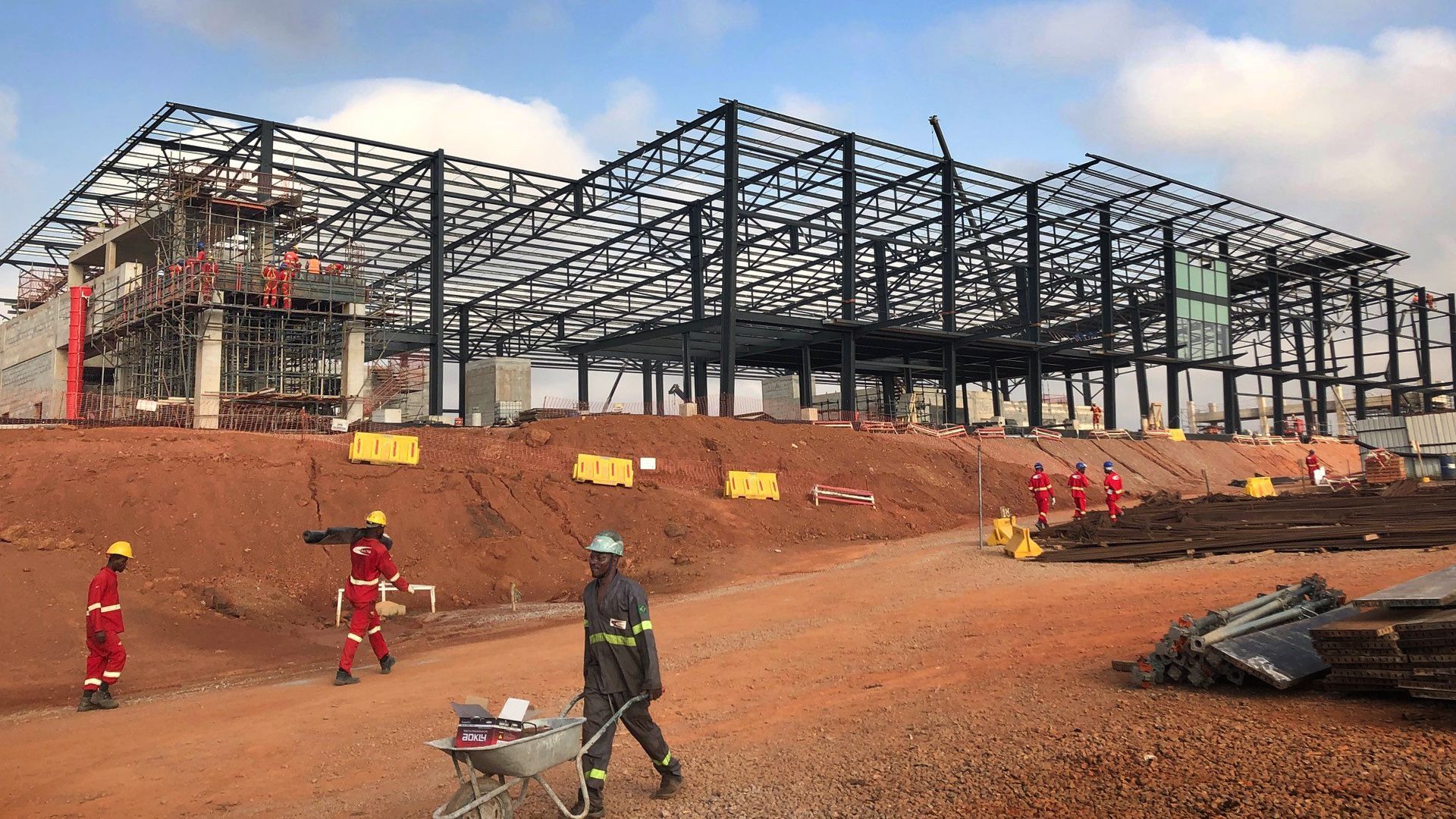 A group of construction workers are standing in front of a large building under construction.