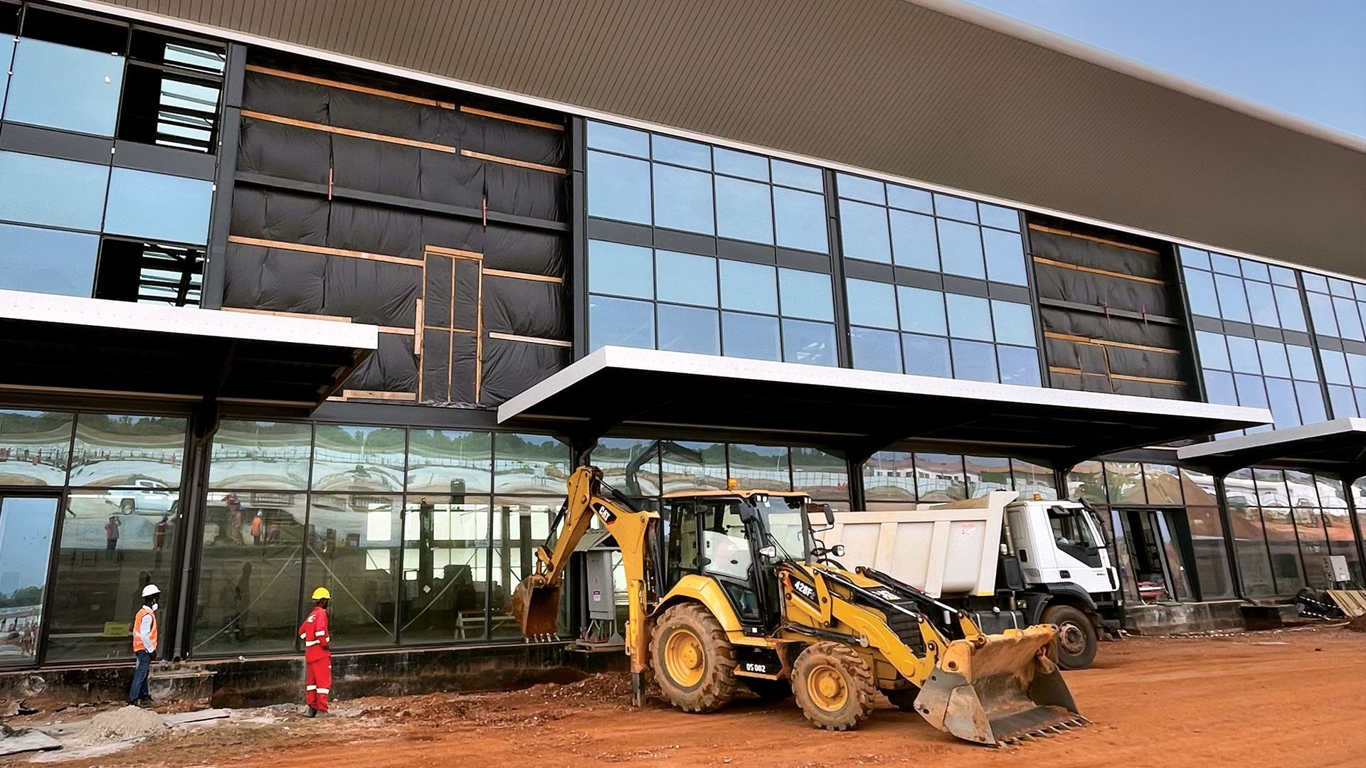 A bulldozer is parked in front of a building under construction.