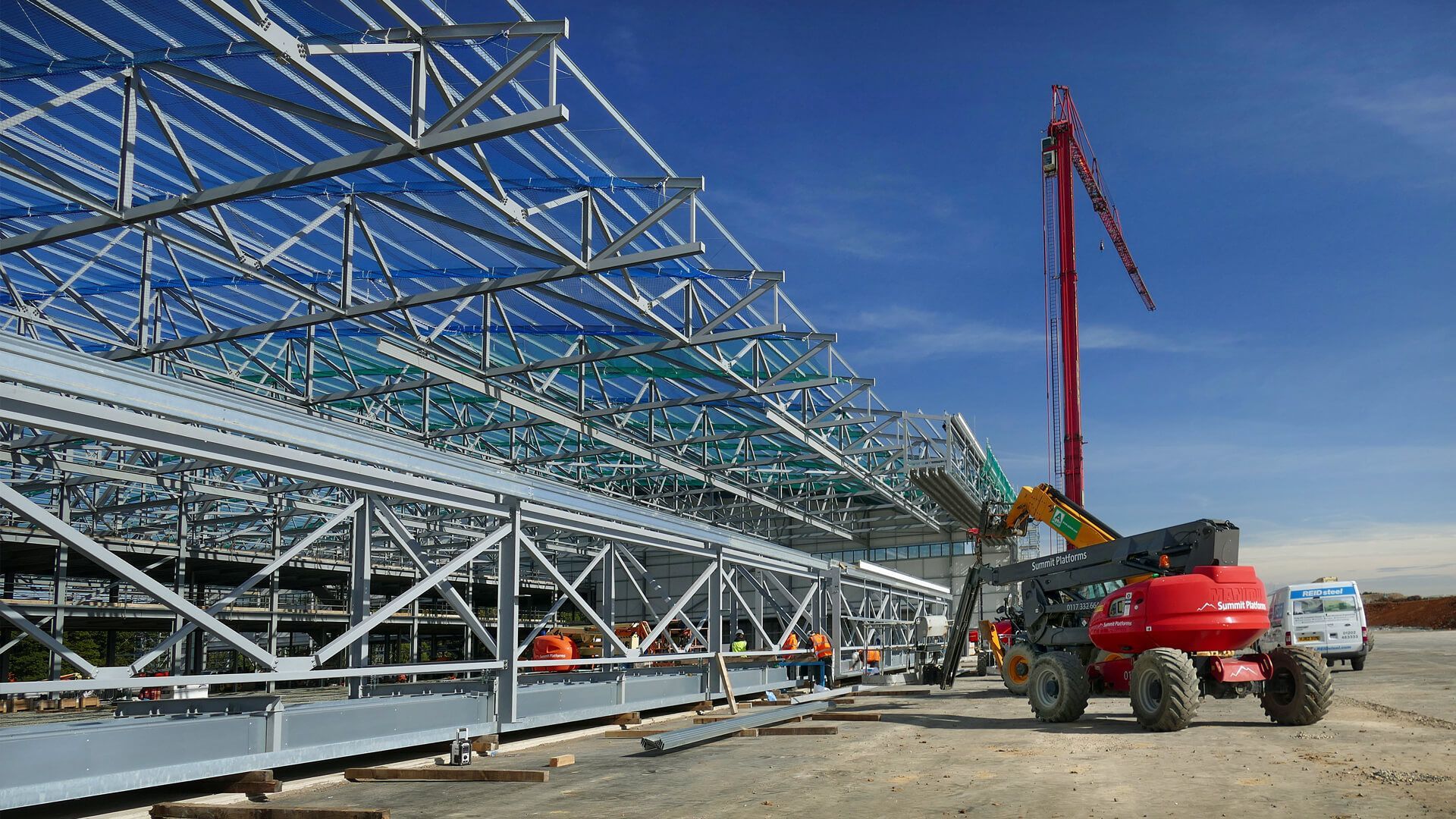 A large metal structure is being built on a construction site.