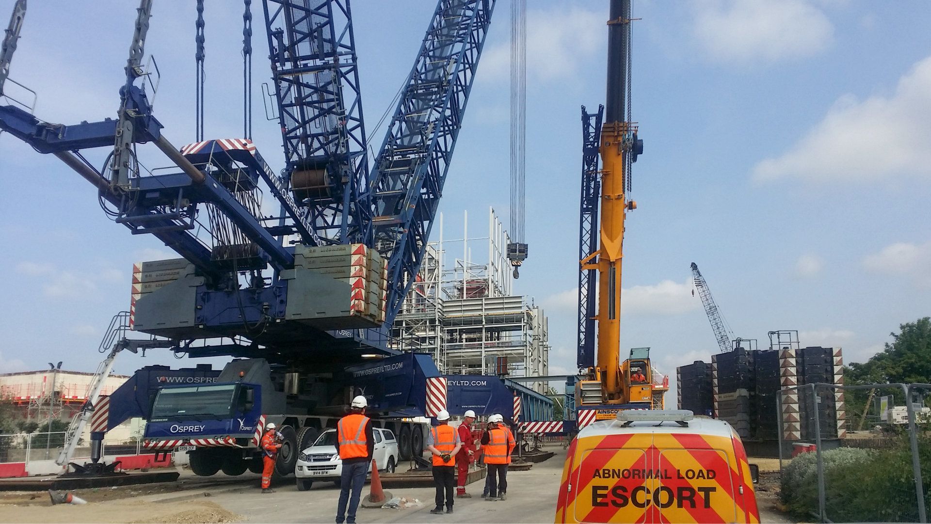 A group of construction workers are standing in front of a large crane.