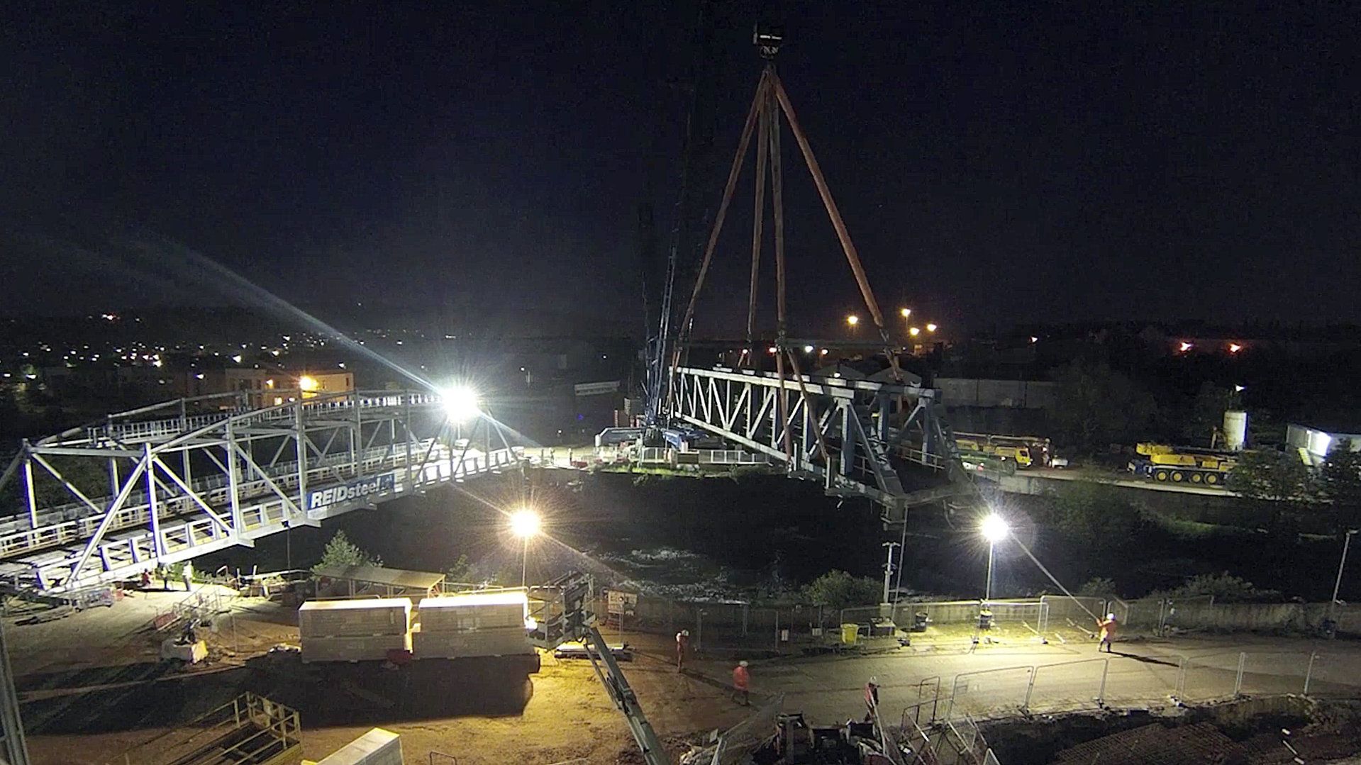A large crane is lifting a bridge at night