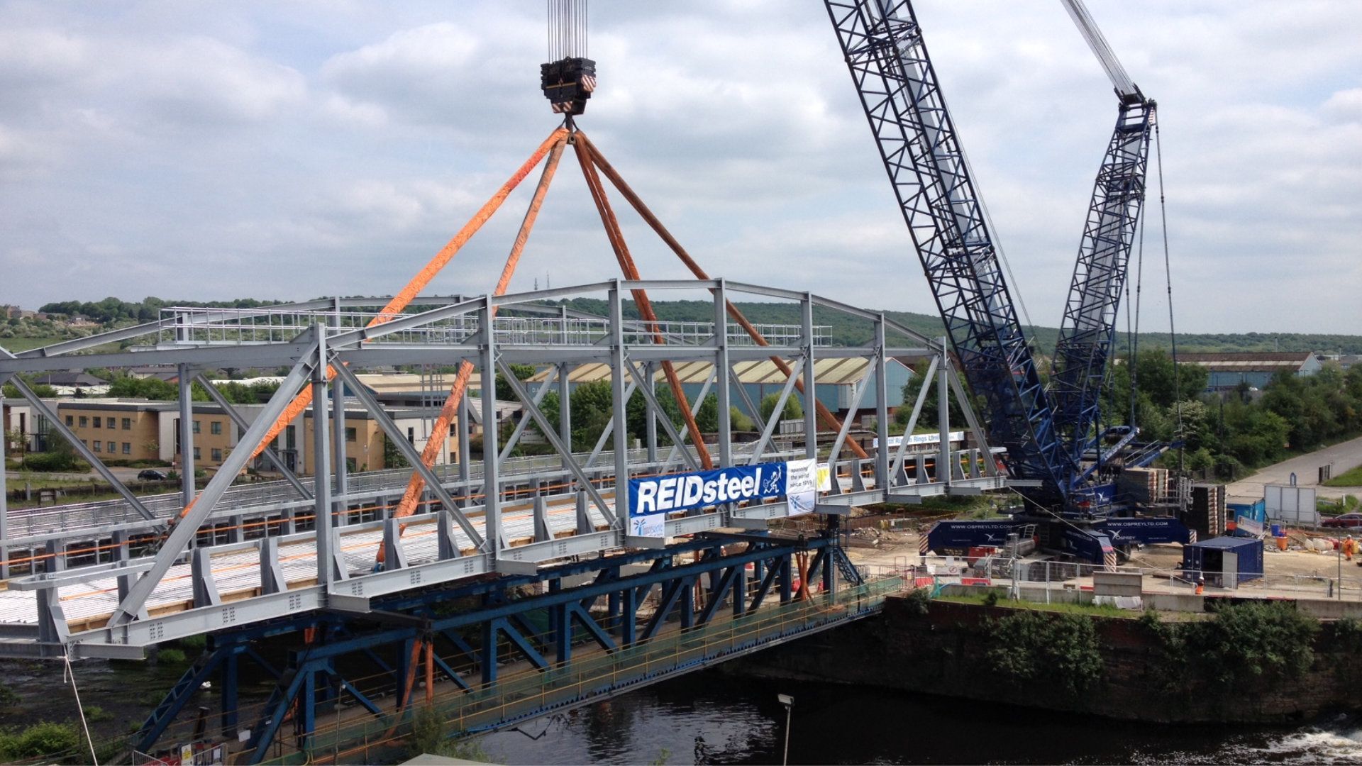 A large crane is lifting a bridge over a river