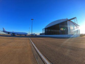 An airplane is parked in front of a  Reidsteel hangar at an airport.