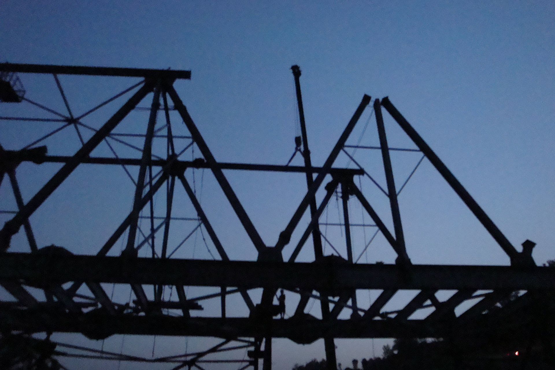 A silhouette of a bridge with a blue sky in the background