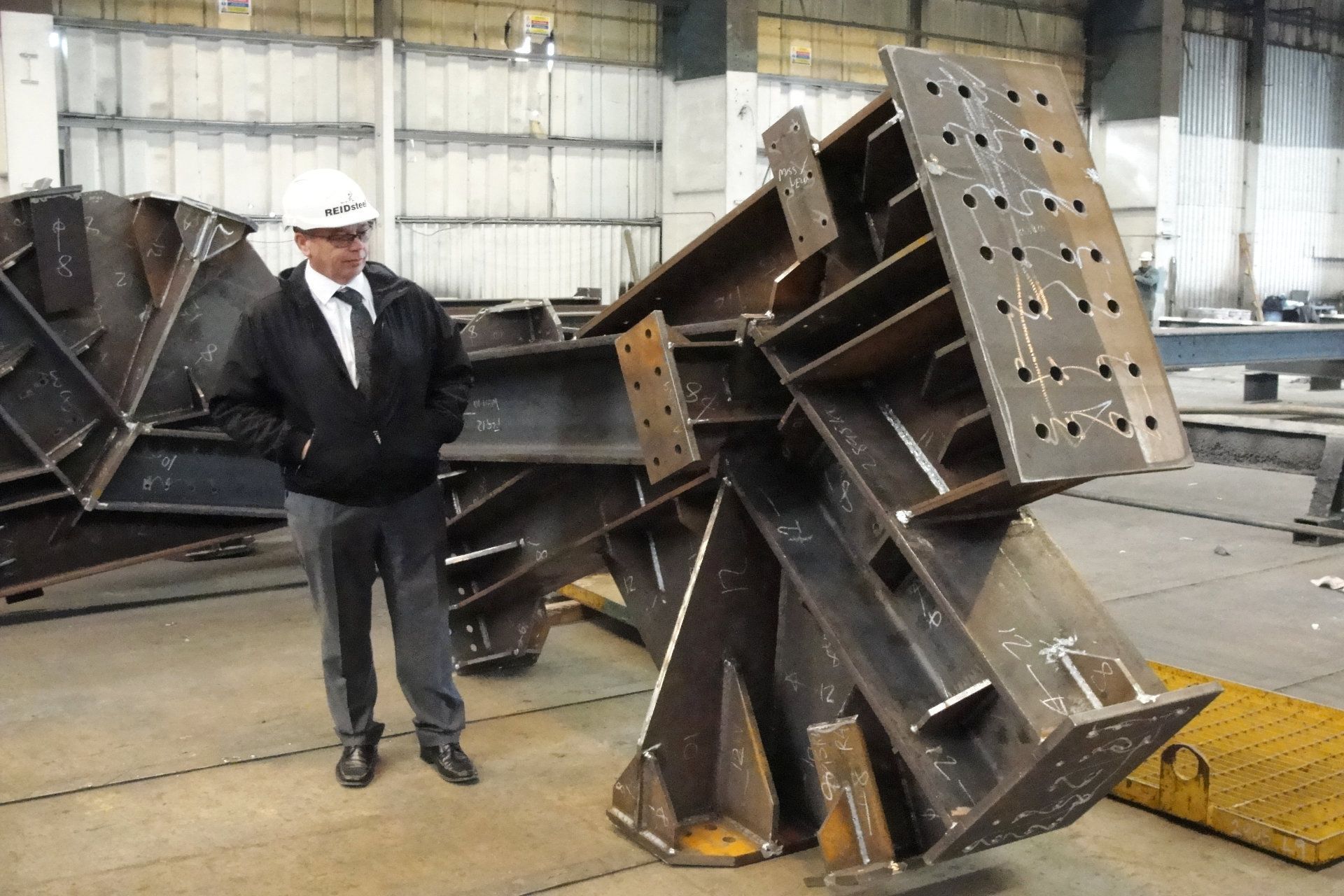 A man in a hard hat is standing next to a large piece of metal