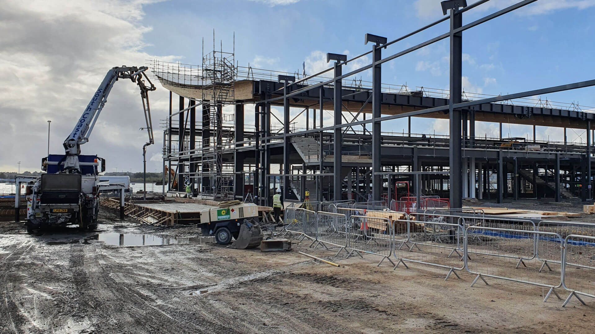 A large building is being built on a muddy construction site.