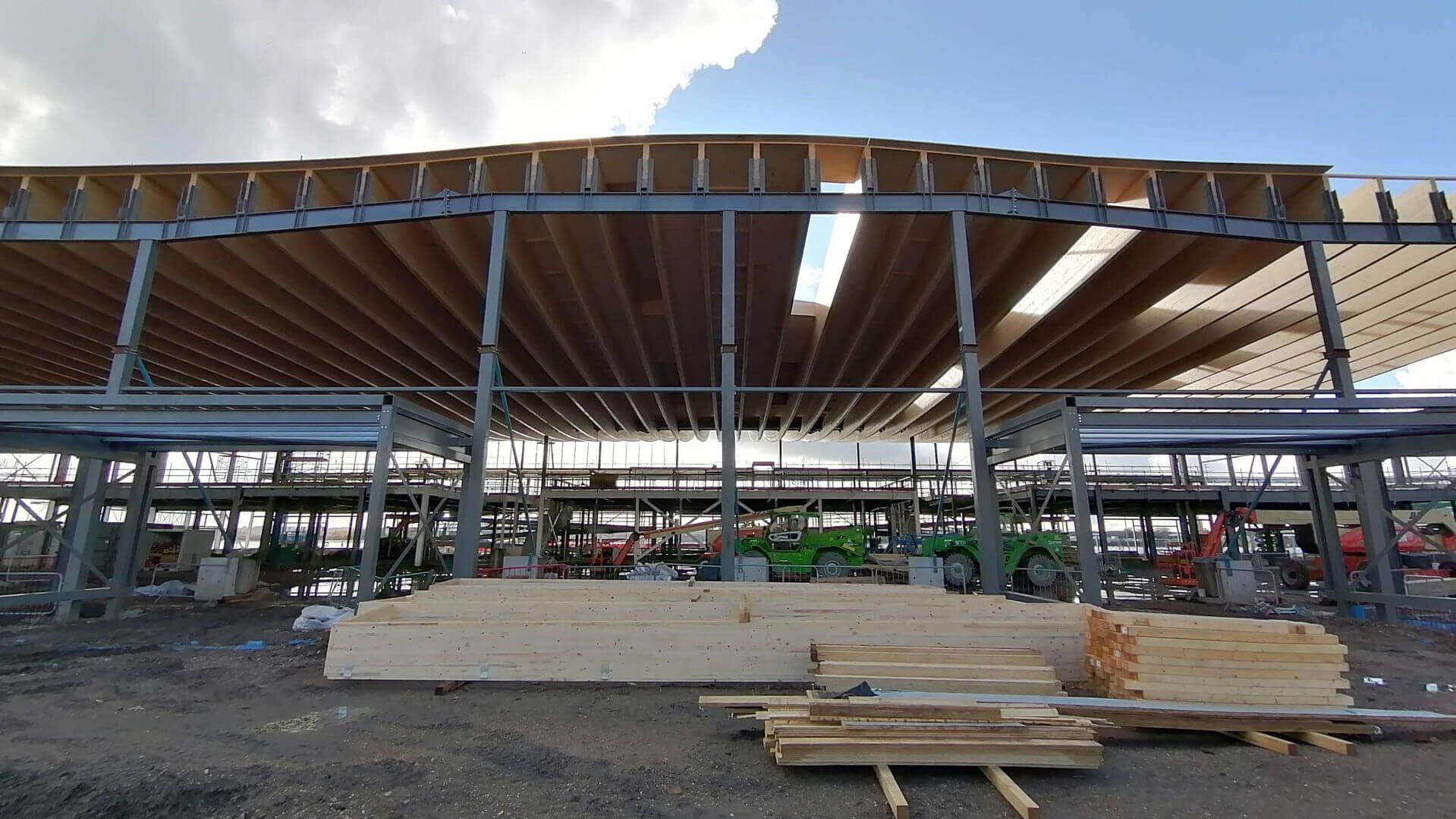 A large building under construction with a lot of wood in front of it