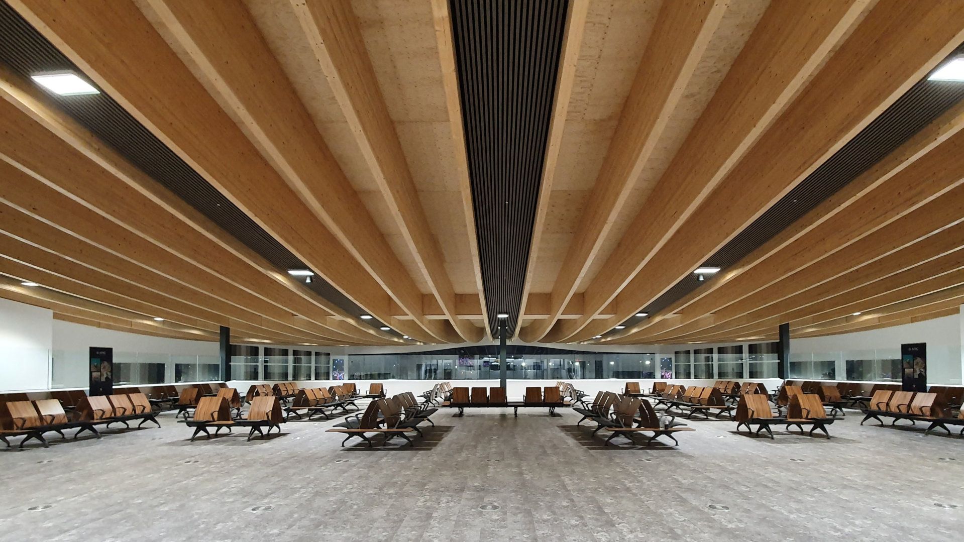 A large waiting room with lots of chairs and a wooden ceiling