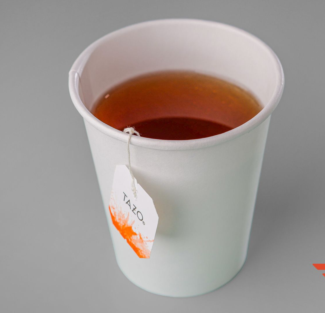 Cup of tea, with a Tazo tea bag, on a light gray surface.