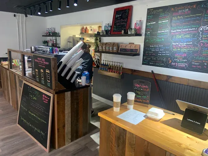 Coffee shop interior with wooden counters, menu boards, and a person behind the counter.