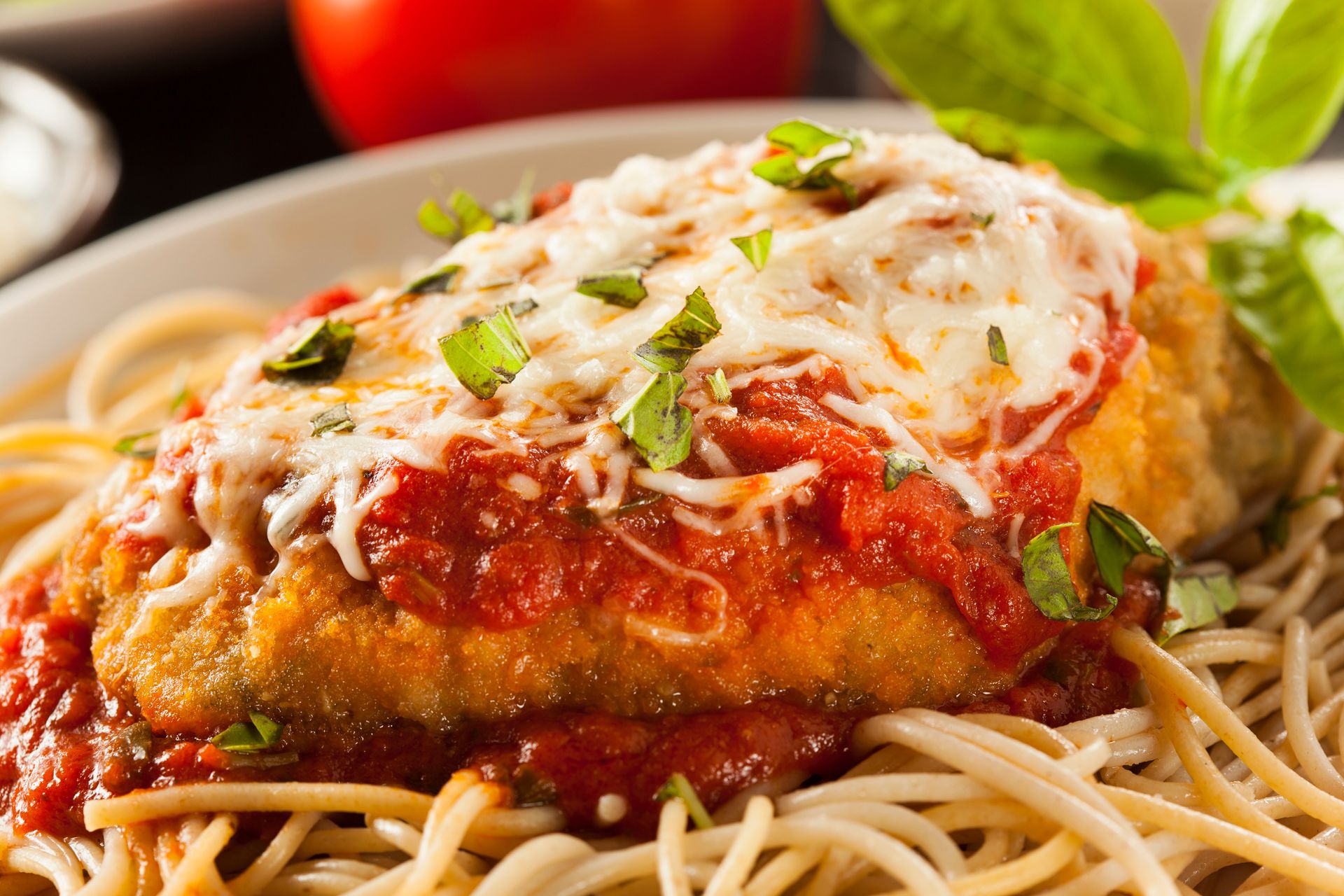 A close up of a plate of chicken parmesan over spaghetti.