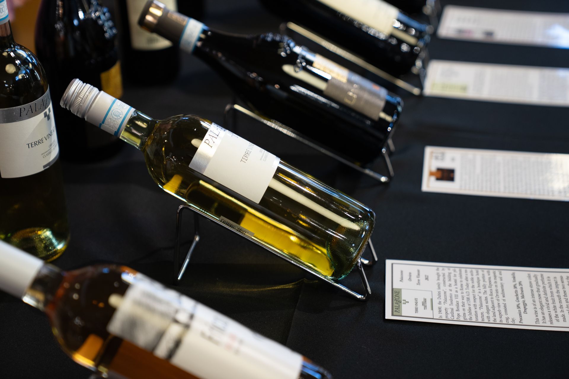 Wine bottles on display at an event, with white and black labels.