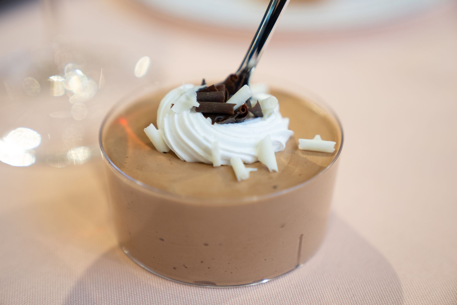Chocolate mousse dessert topped with whipped cream and chocolate shavings in a clear cup.