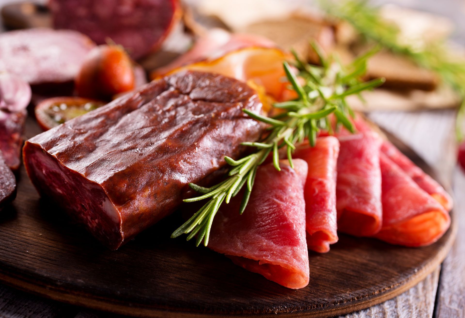 Charcuterie board with sliced meats, garnished with rosemary.
