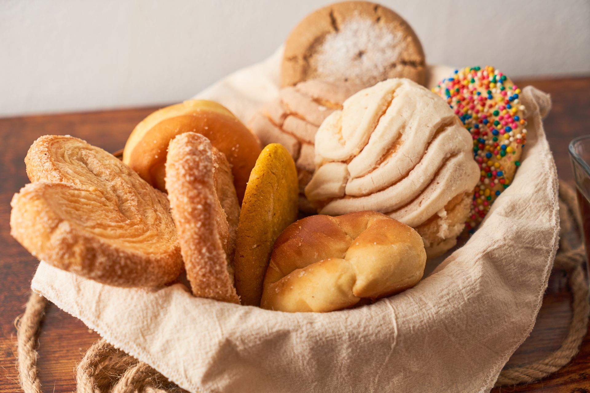 Basket filled with various Mexican sweet breads, including conchas and palmiers.