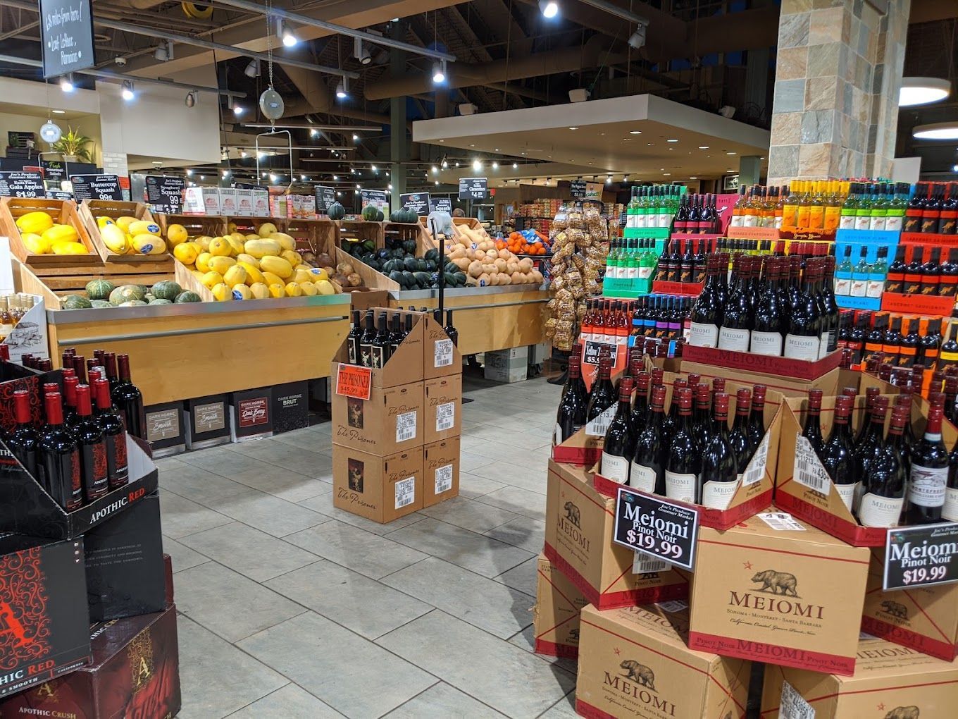 Interior of a grocery store with produce and wine displays.