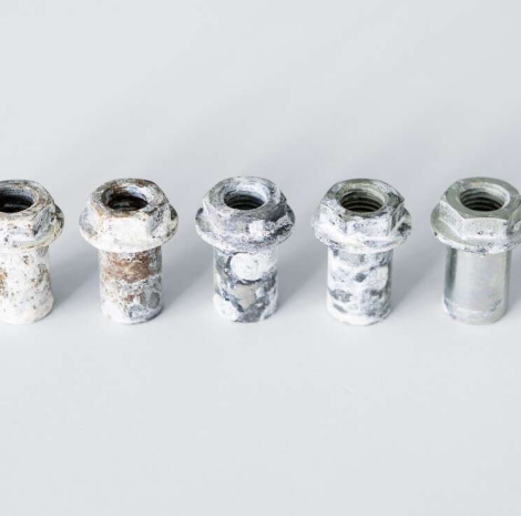 Una fila de nueces oxidadas están alineadas sobre una superficie blanca.