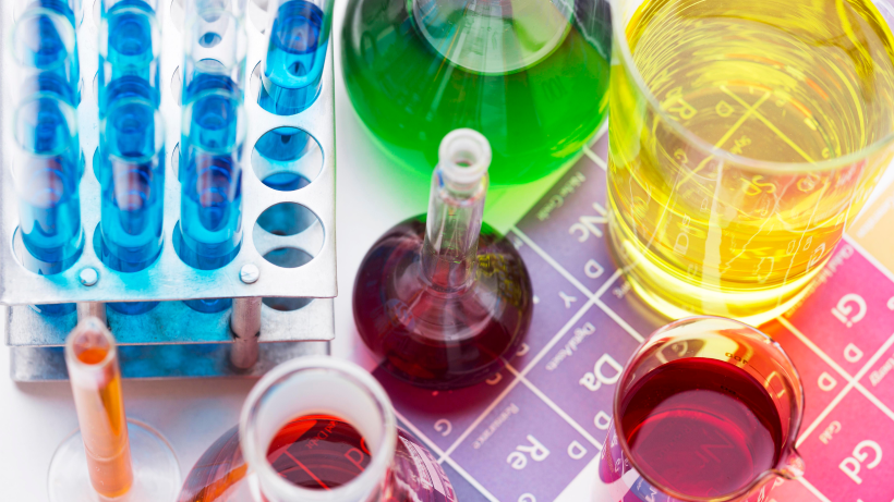 Un montón de vasos llenos de líquidos de diferentes colores sobre una mesa.