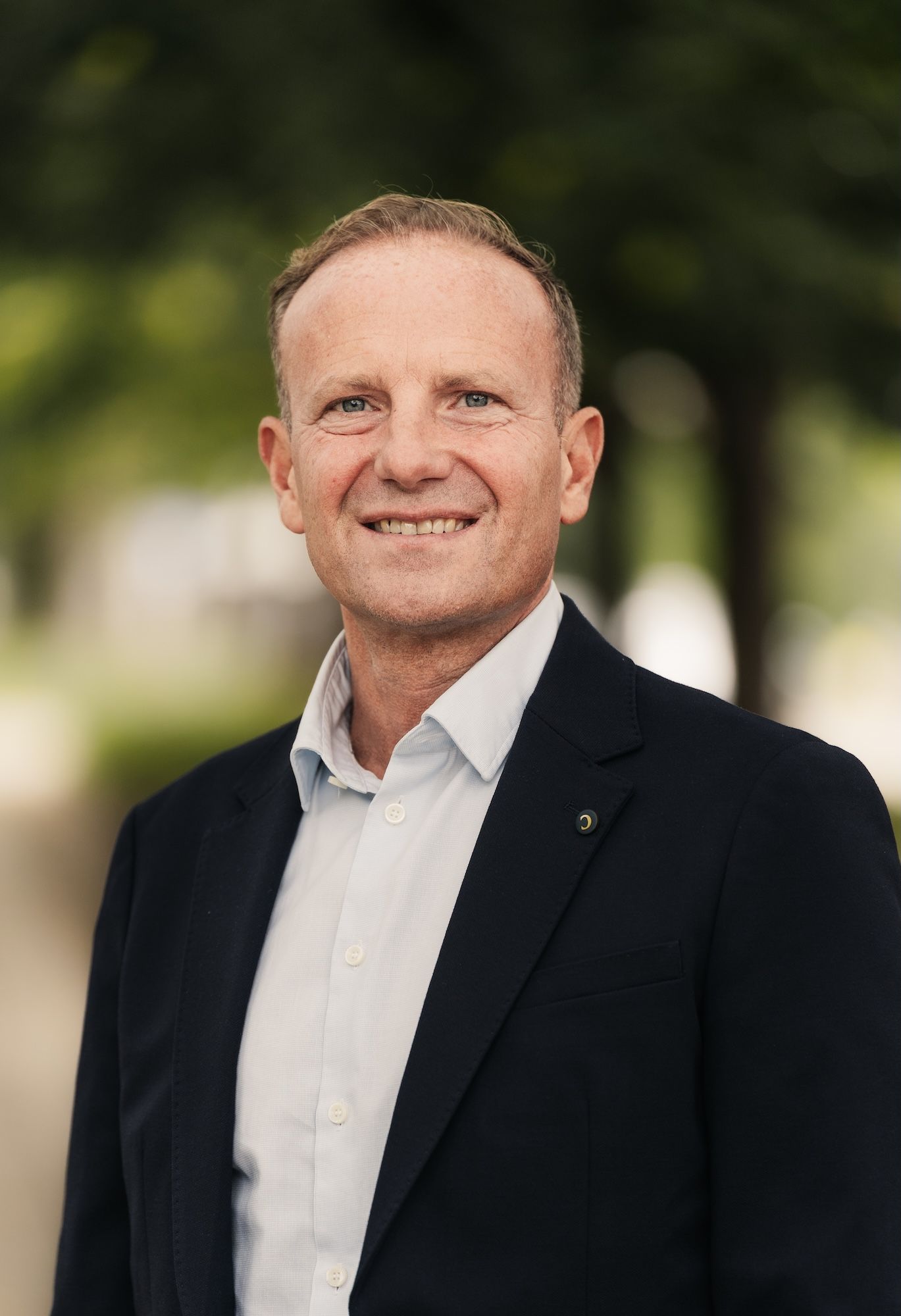Een profielfoto van een medewerkster van Donkey Mobile, buiten met bomen op de achtergrond.