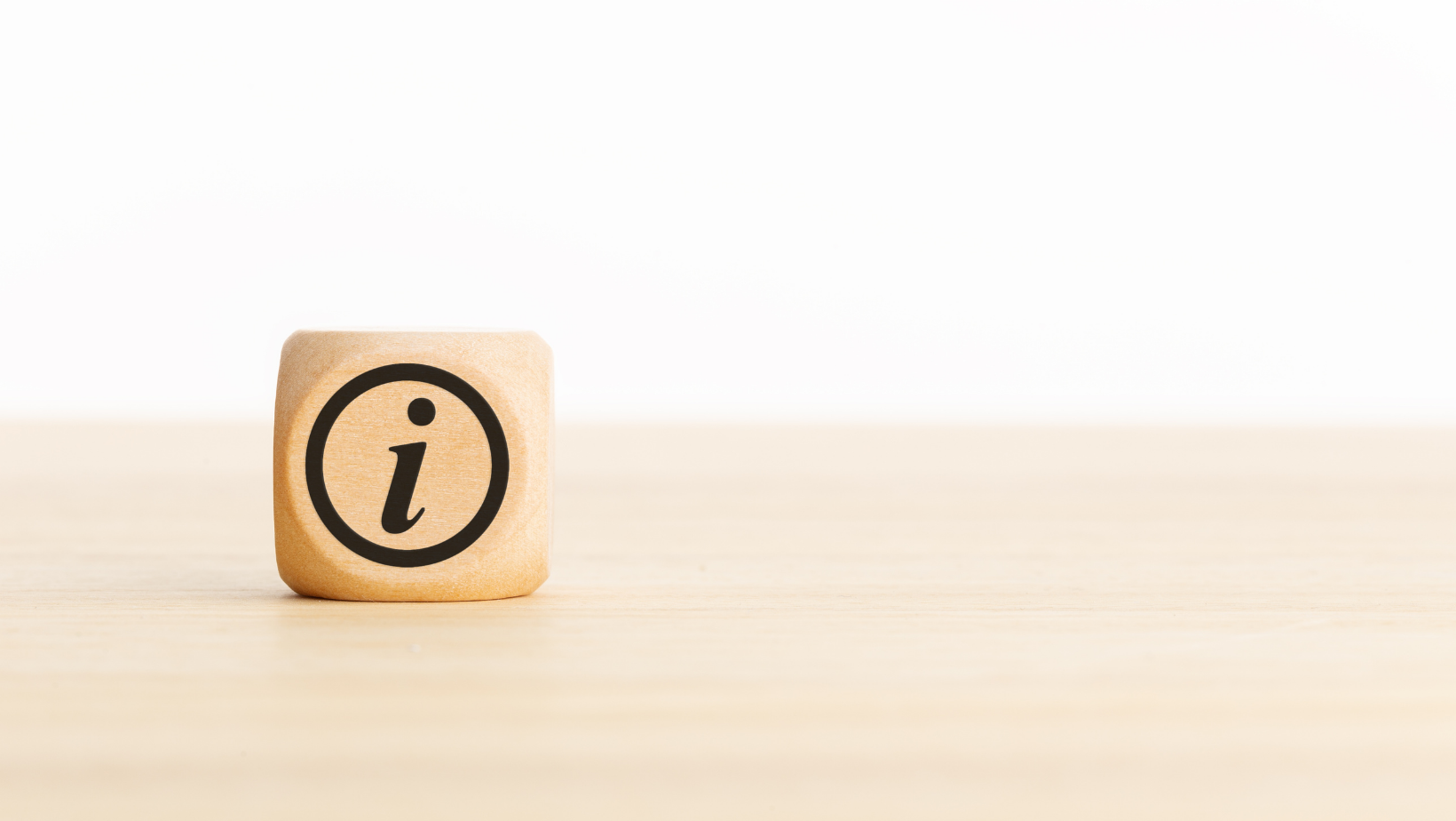 Een houten kubus met de letter i erop staat op een houten tafel.