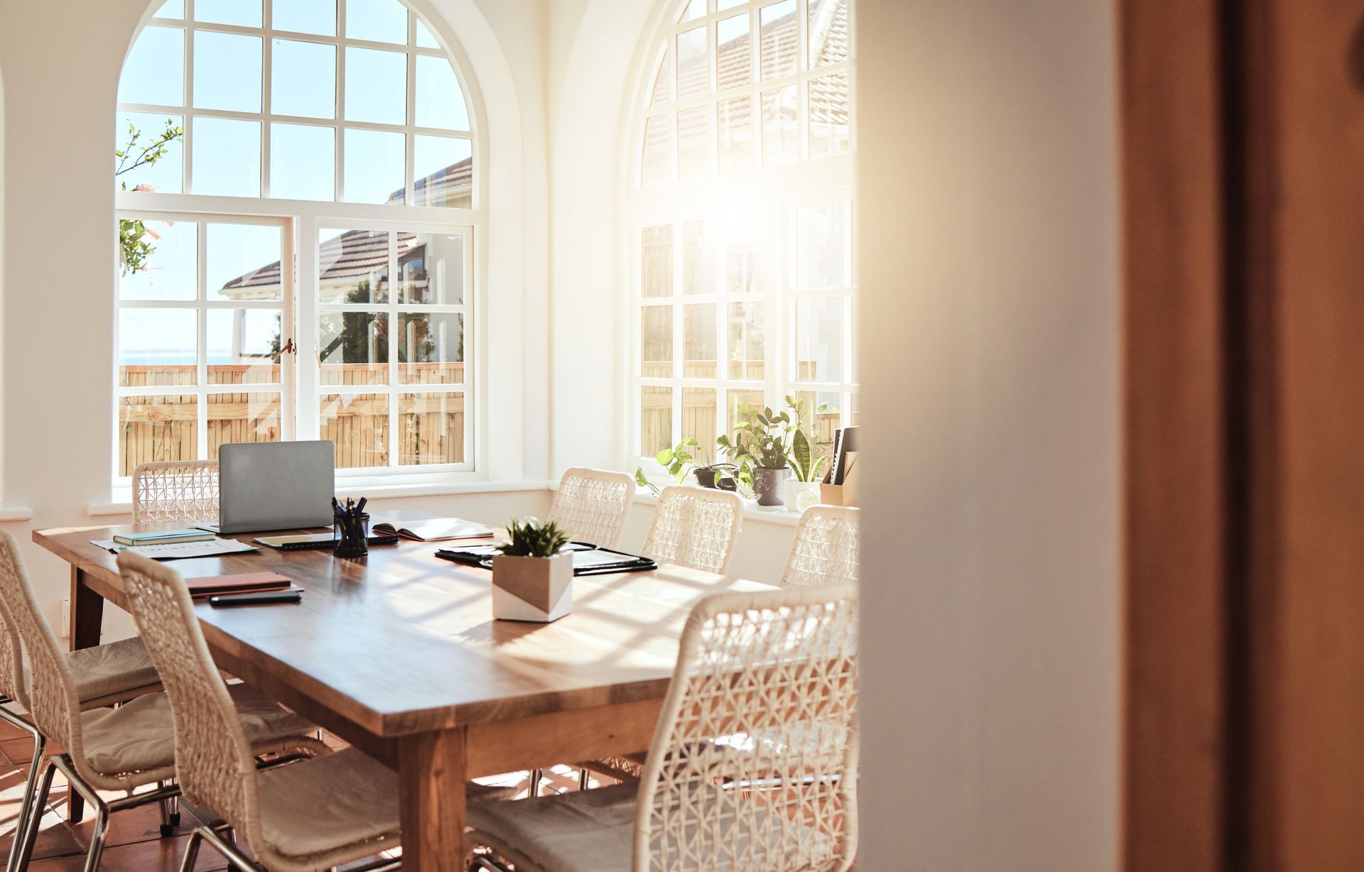 A conference room with a long wooden table and chairs and a laptop on it.