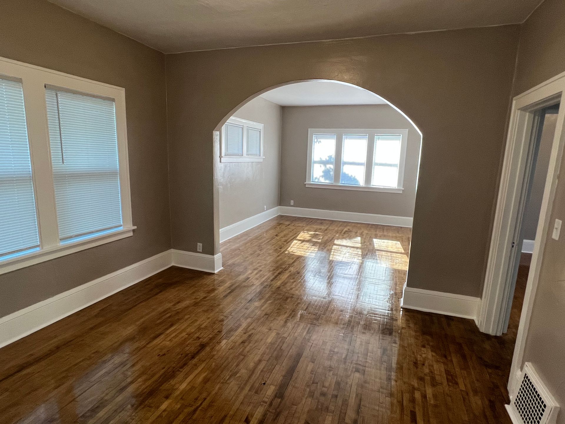 An empty living room with hardwood floors and a window.