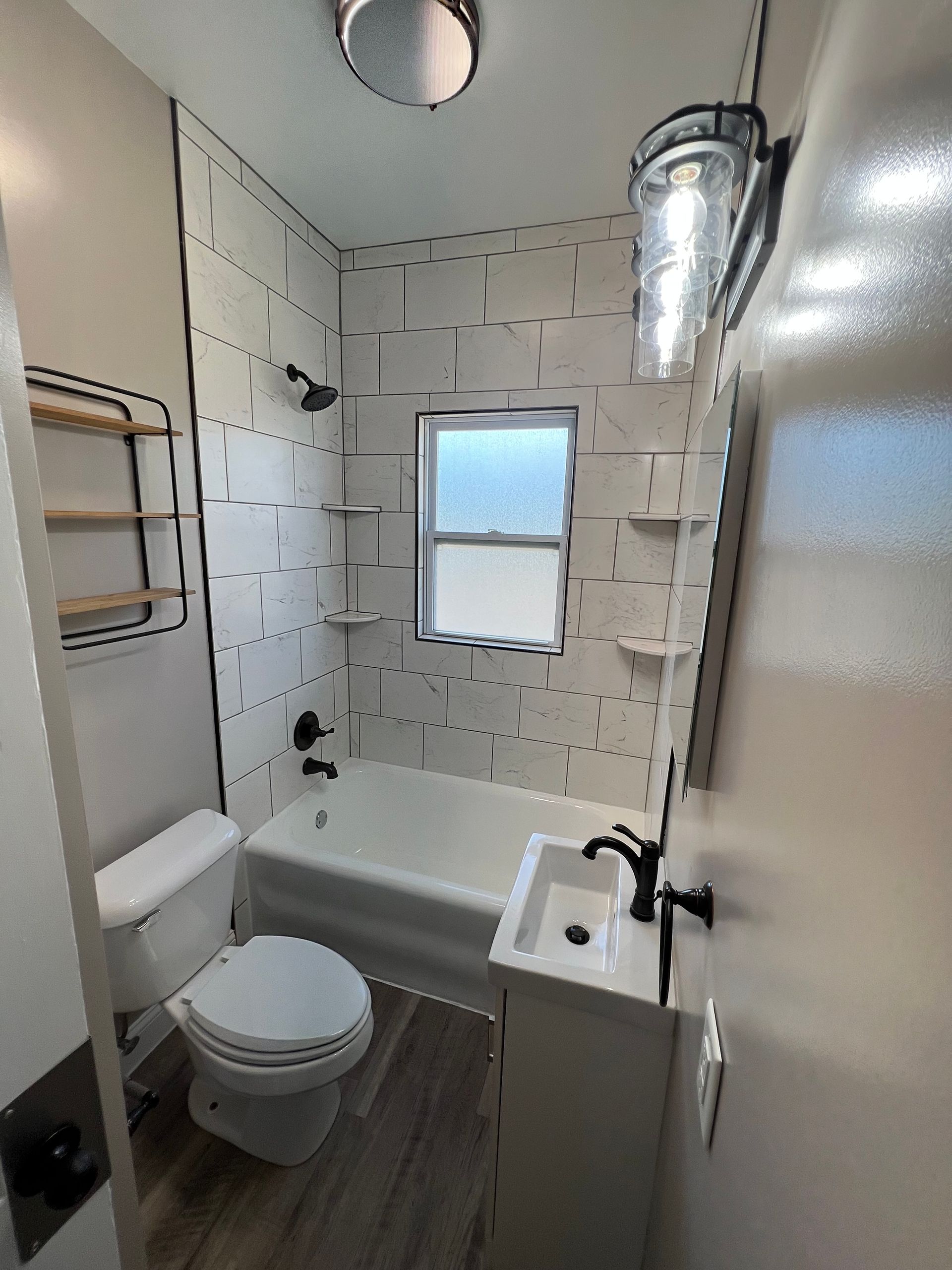 A bathroom with a toilet , sink , bathtub and window.