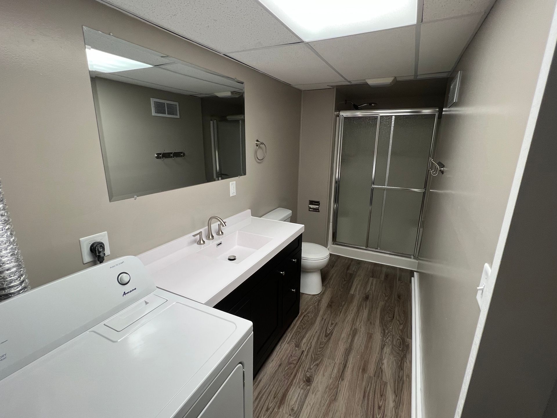 A bathroom with a washer and dryer , sink , toilet and shower.