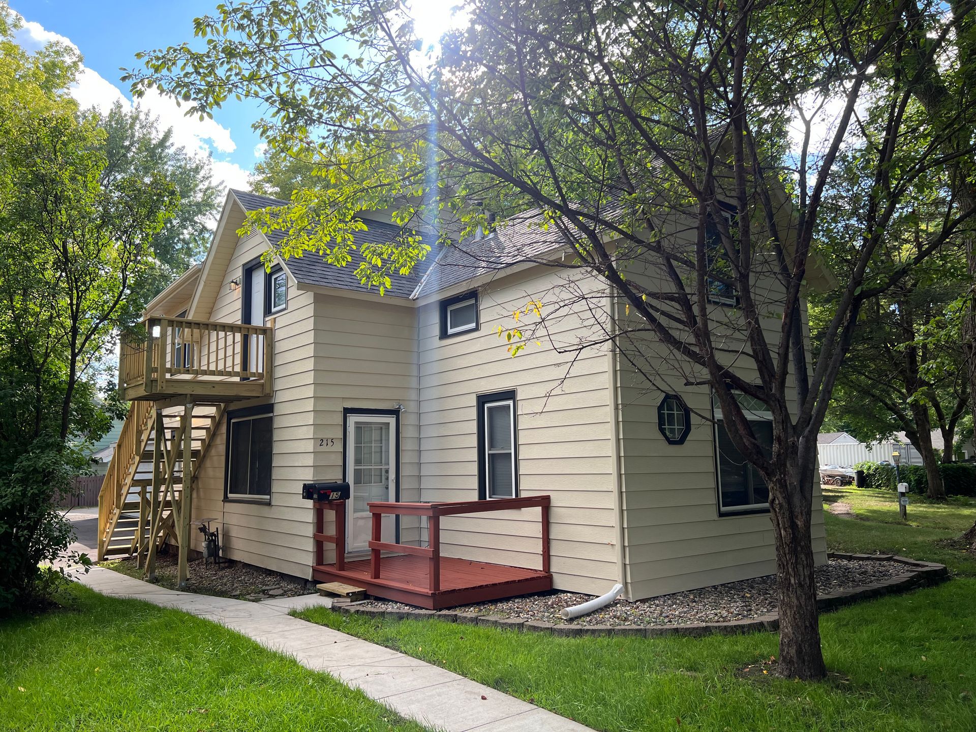 A small white house with a wooden deck and stairs.