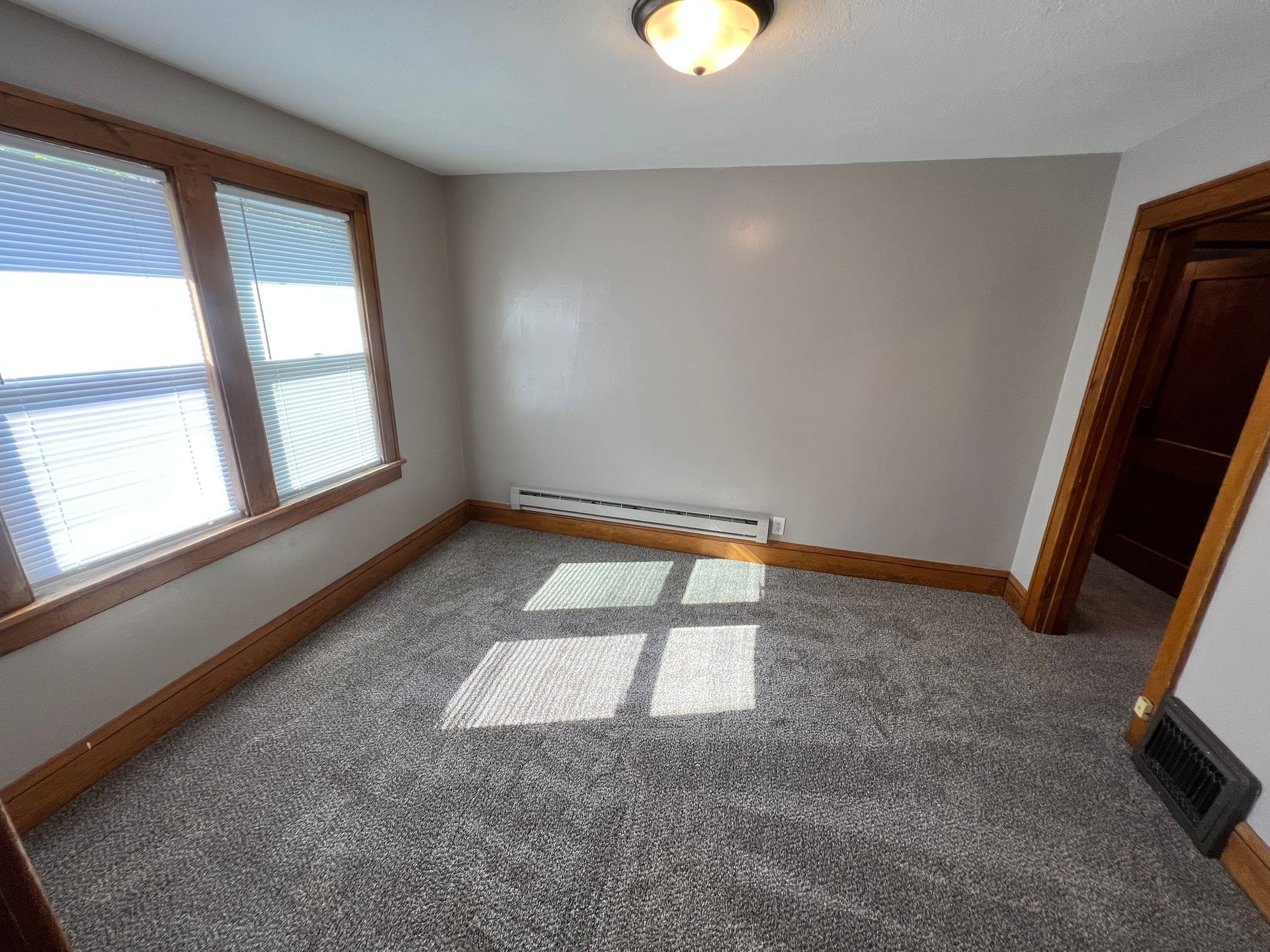 An empty room with a lot of windows and a carpeted floor.