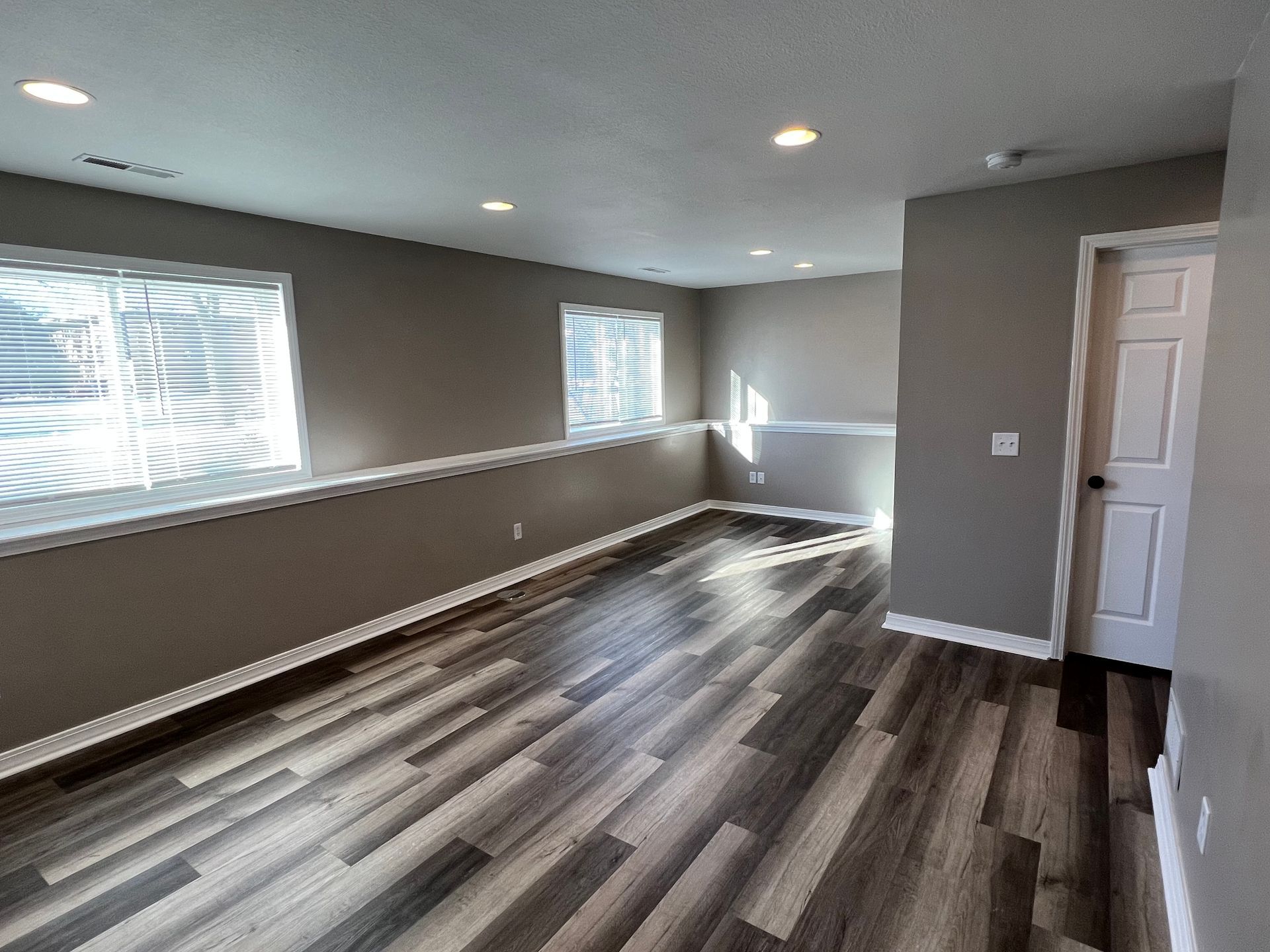 An empty living room with hardwood floors and a door.