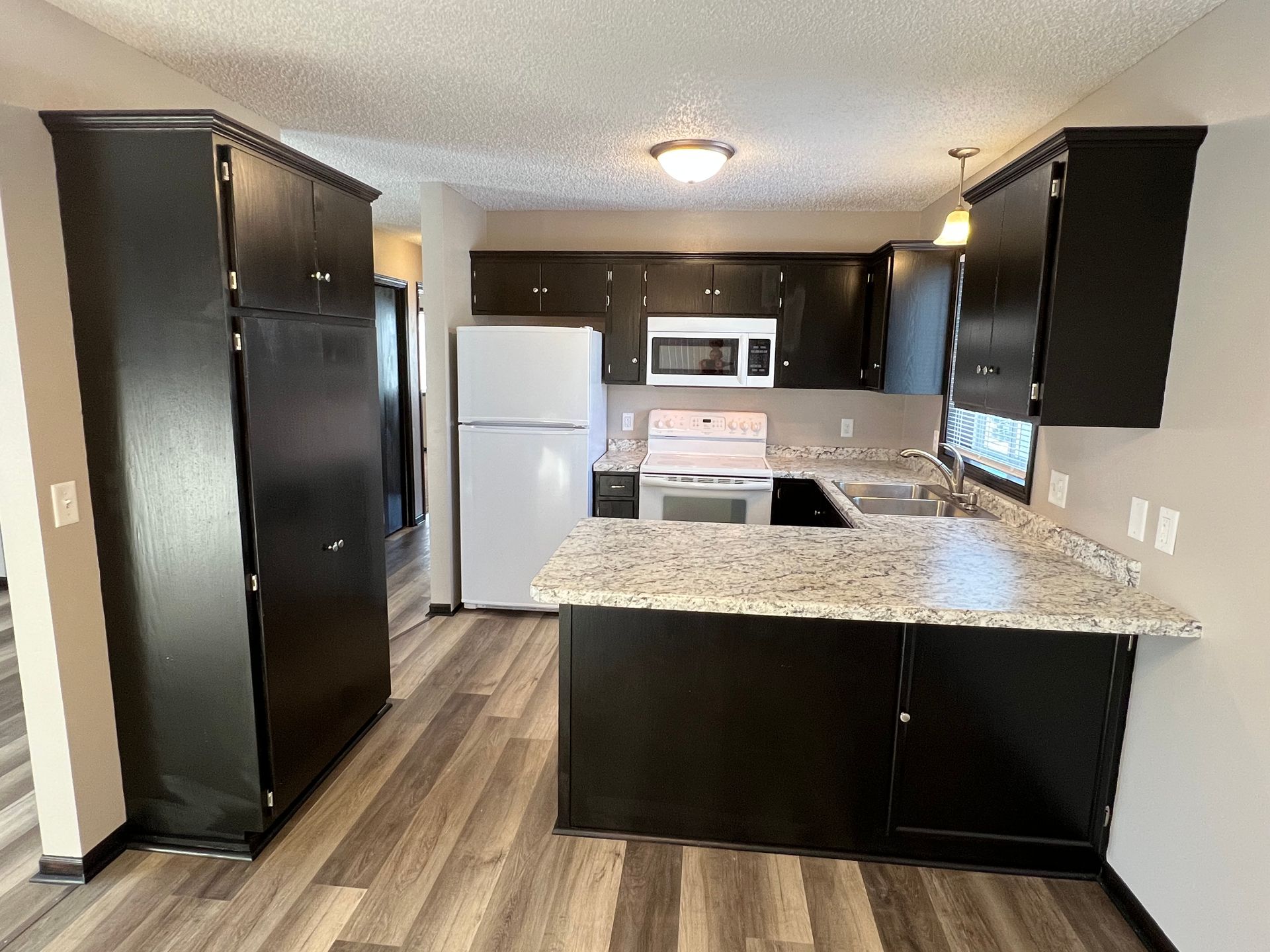 A kitchen with black cabinets and a white refrigerator