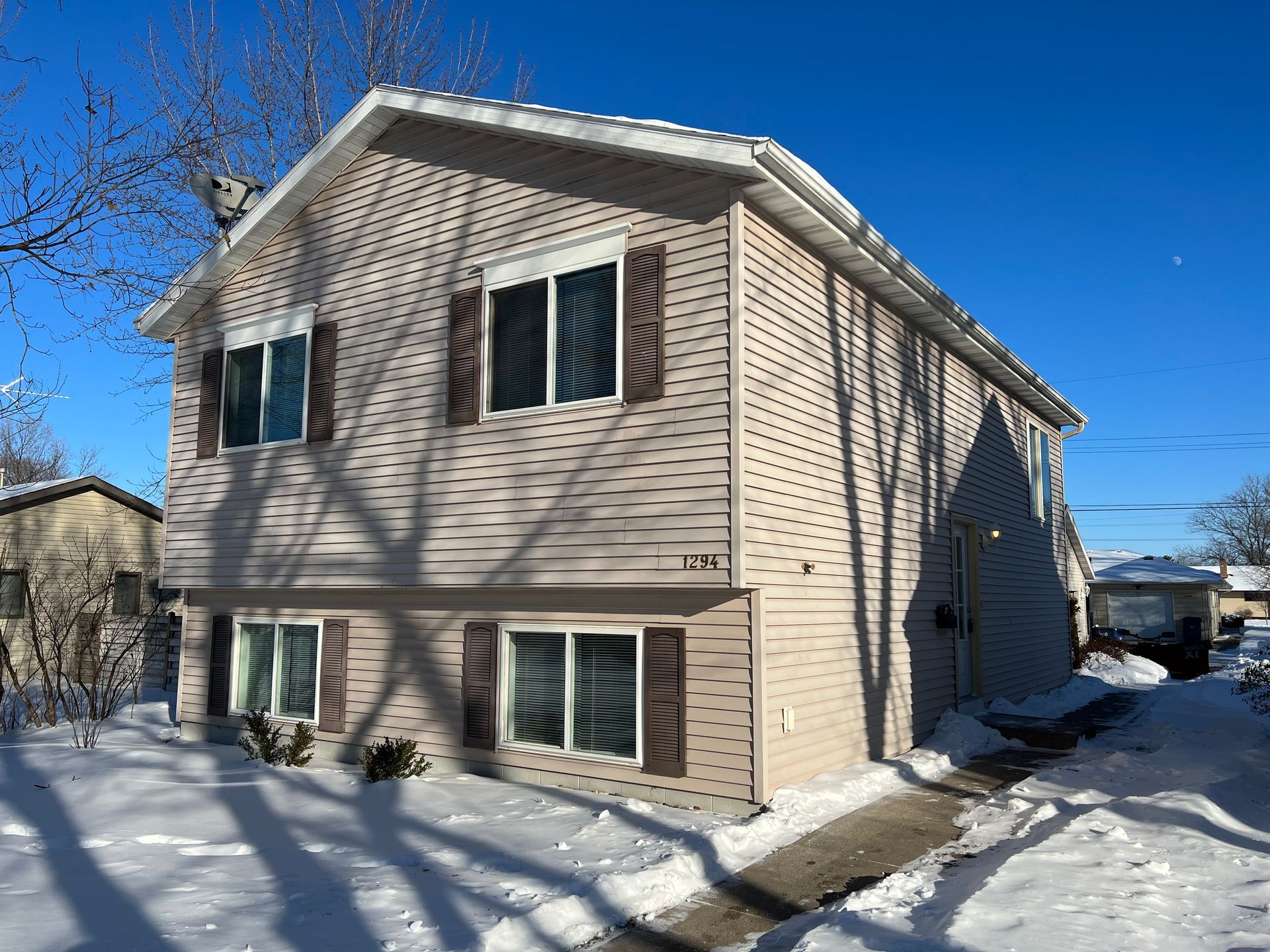 A house with a lot of windows is covered in snow