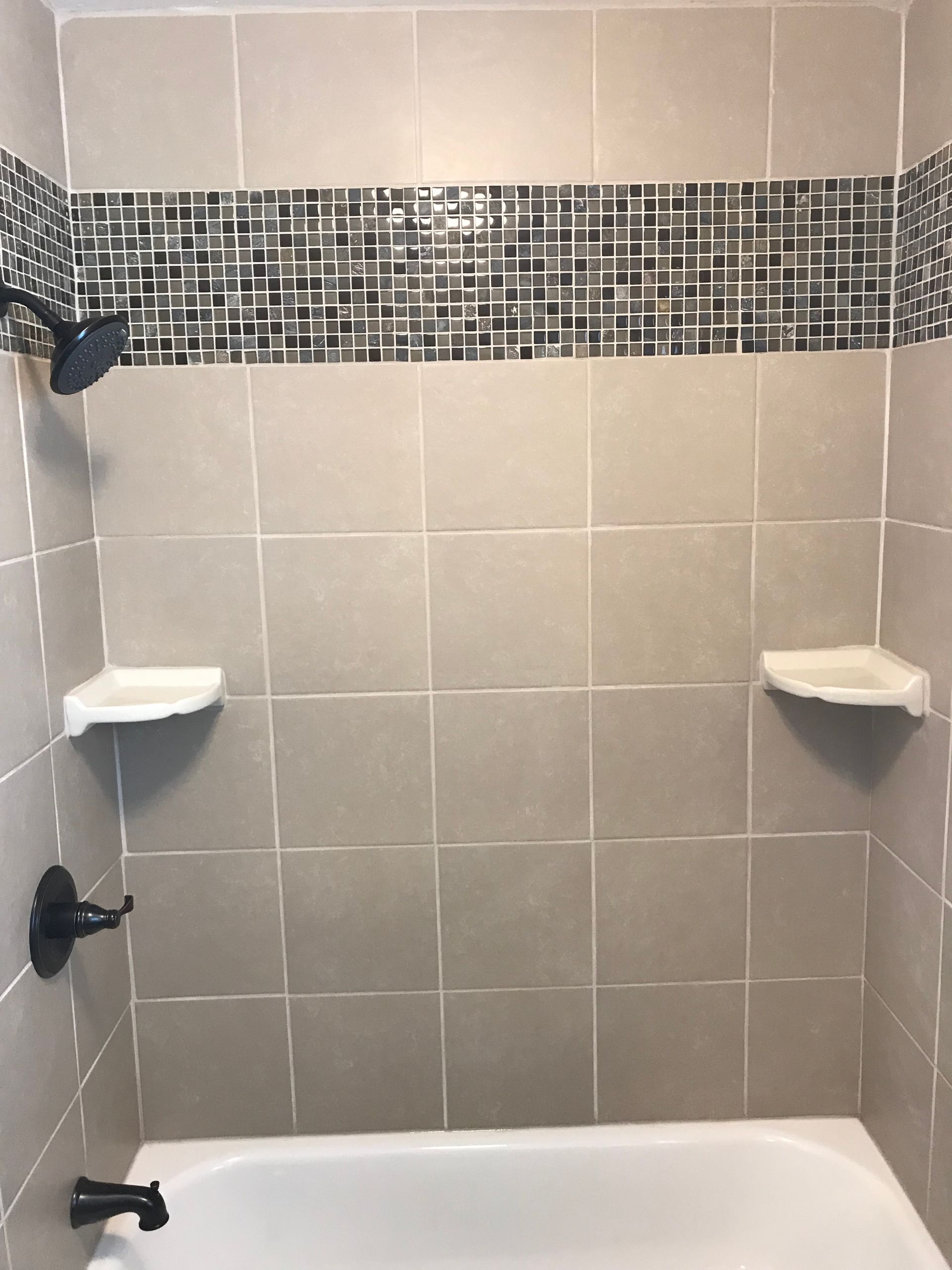 A bathtub in a bathroom with a shower and shelves