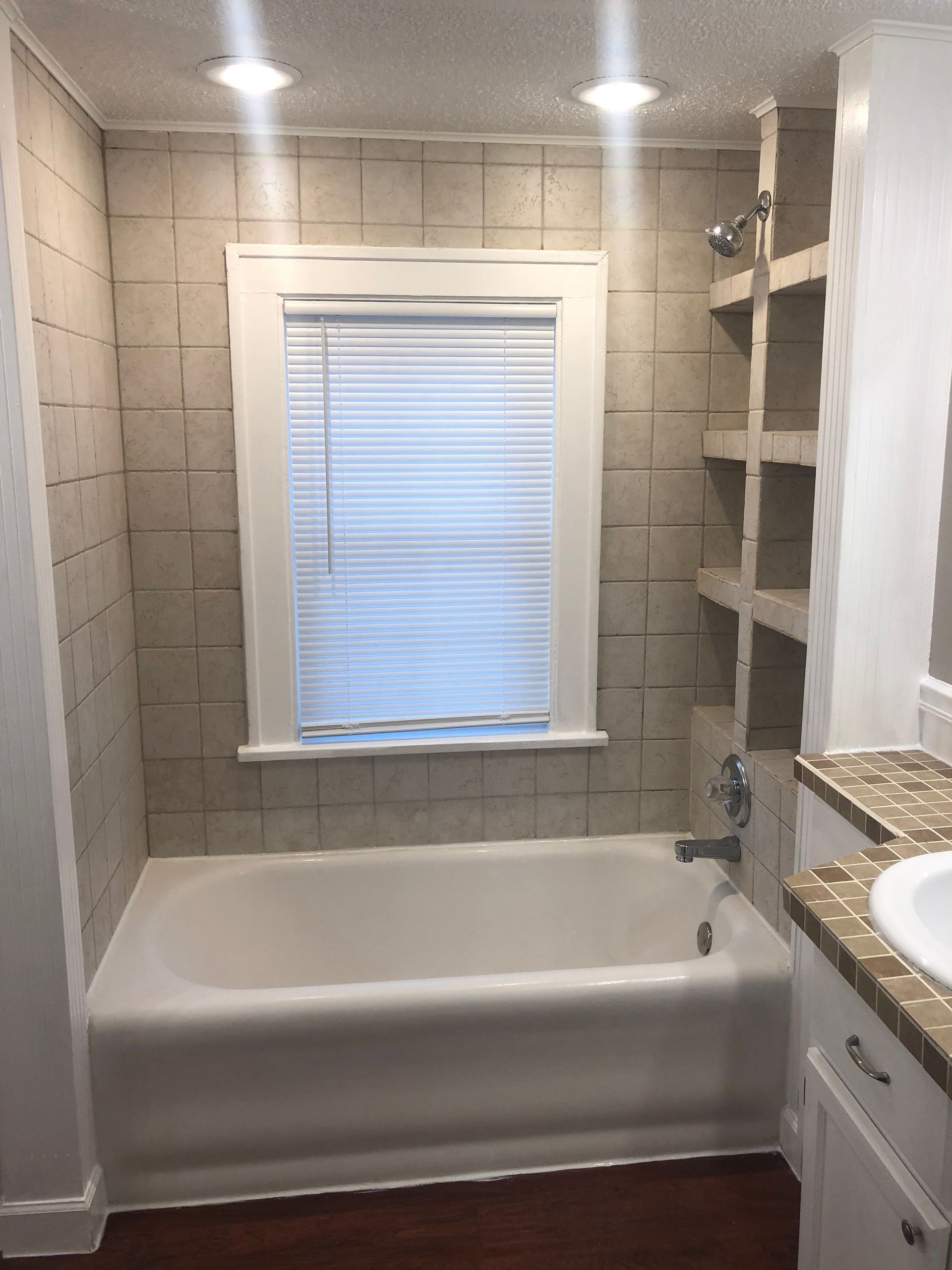 A bathroom with a tub , sink , and window.