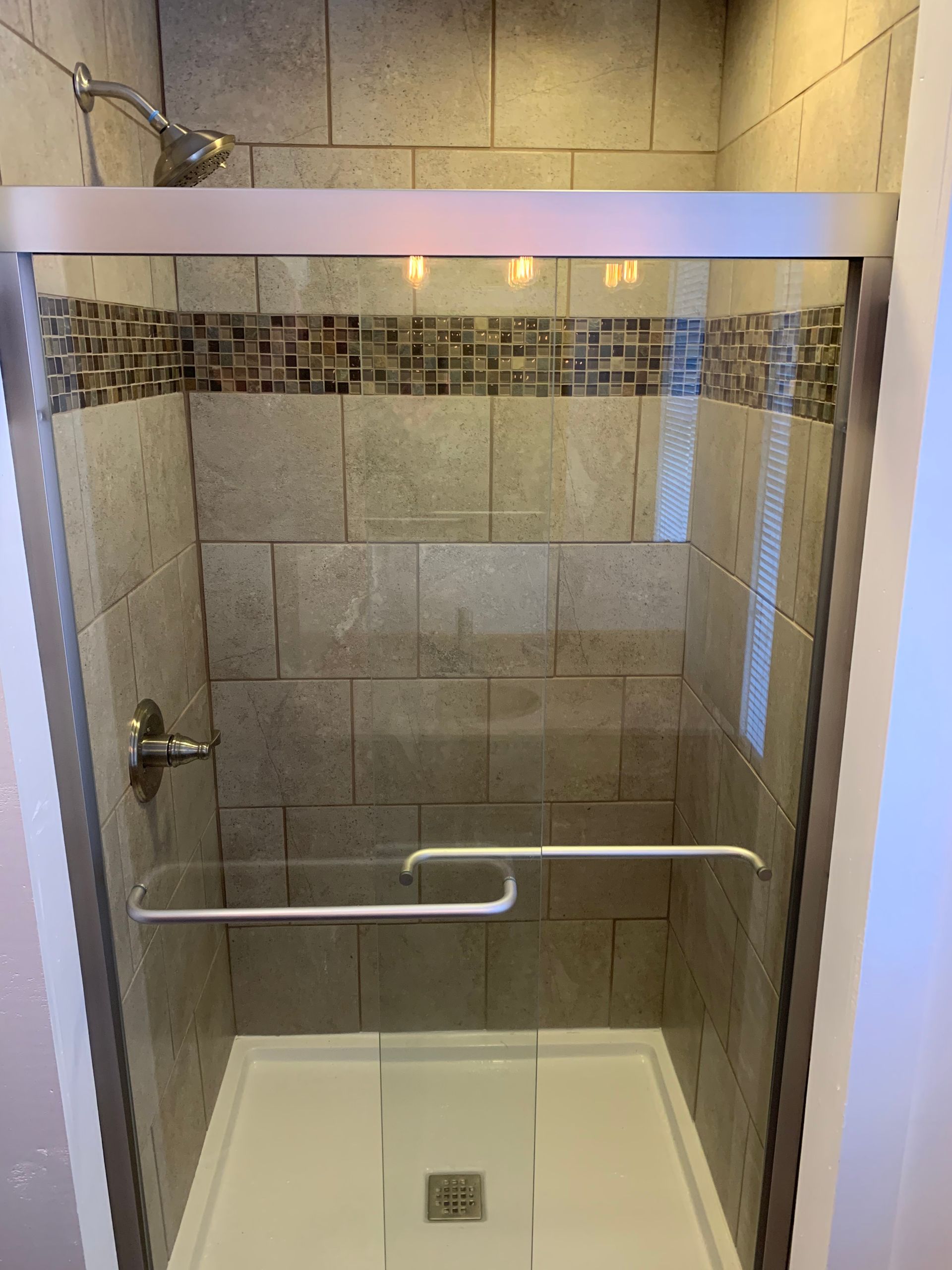 A shower with a sliding glass door and a shower head