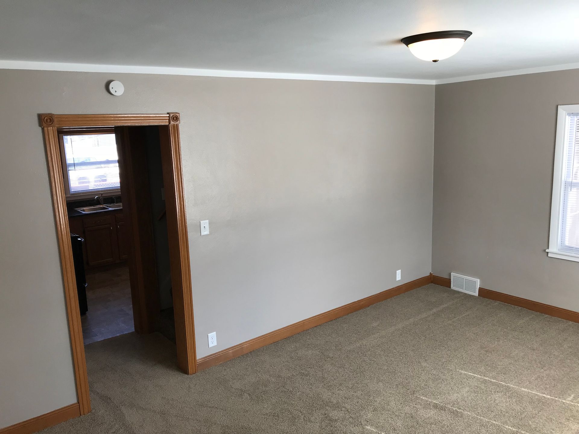 An empty living room with a doorway leading to a kitchen.