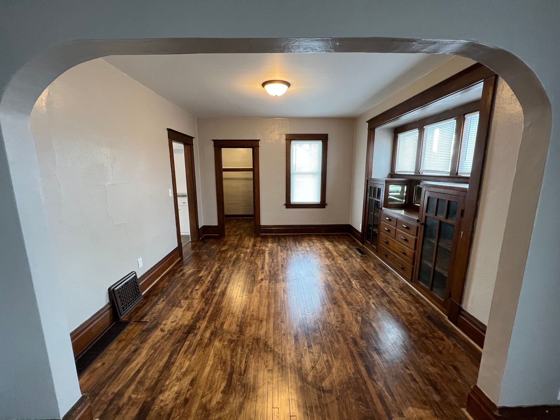 An empty living room with hardwood floors and a window