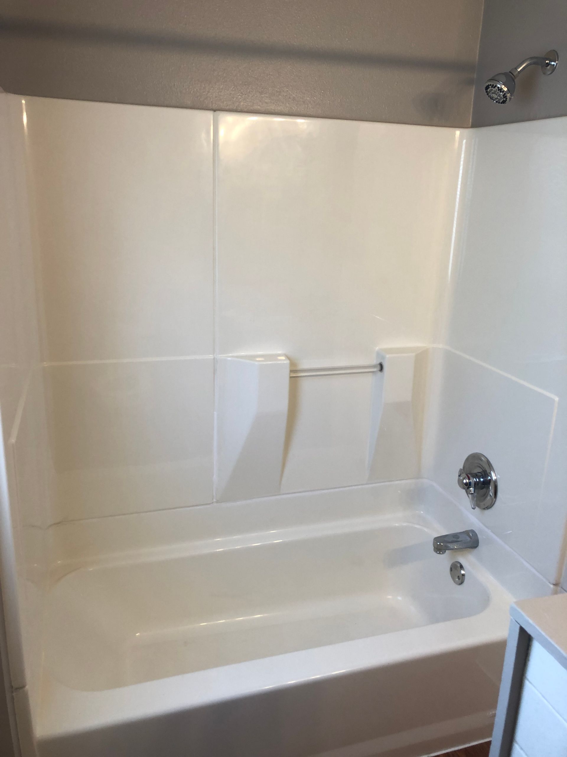 A white bathtub in a bathroom with white tiles