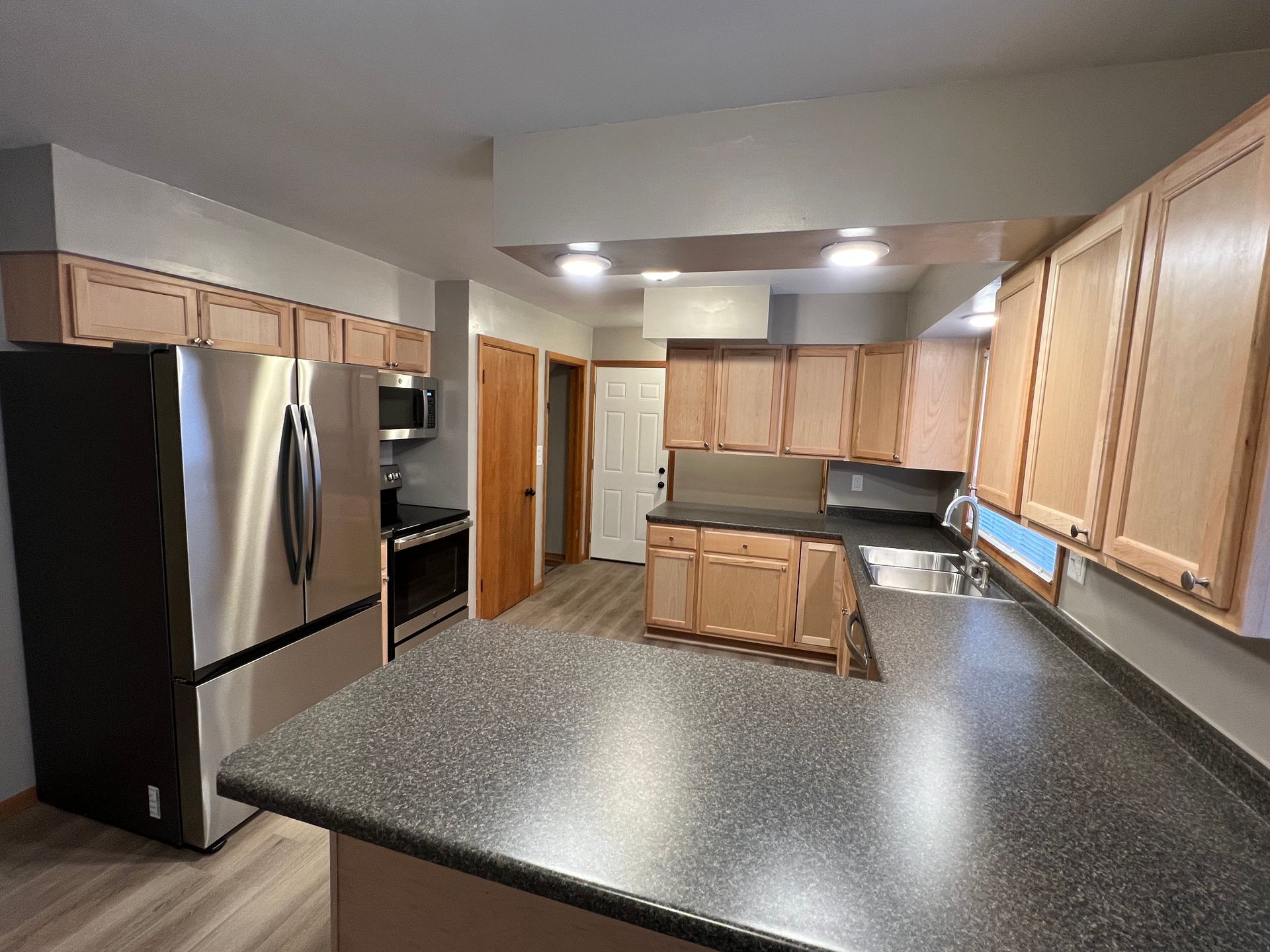 A kitchen with stainless steel appliances , granite counter tops , and wooden cabinets.