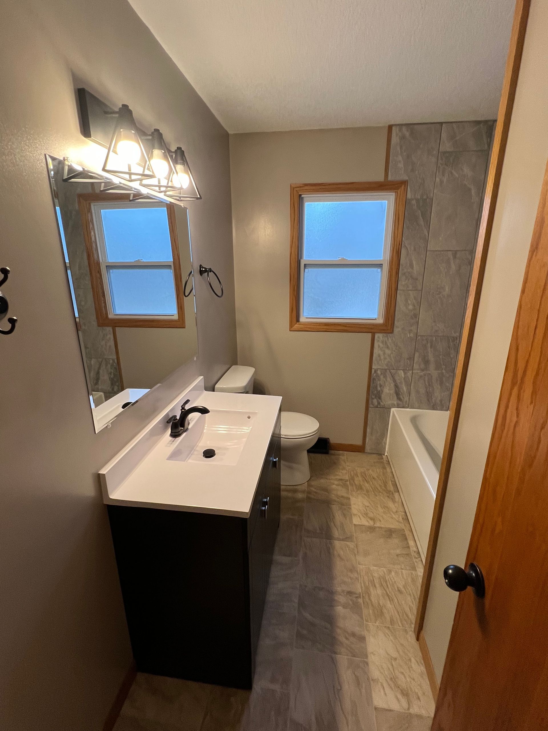 A bathroom with a sink , toilet , tub and mirror.
