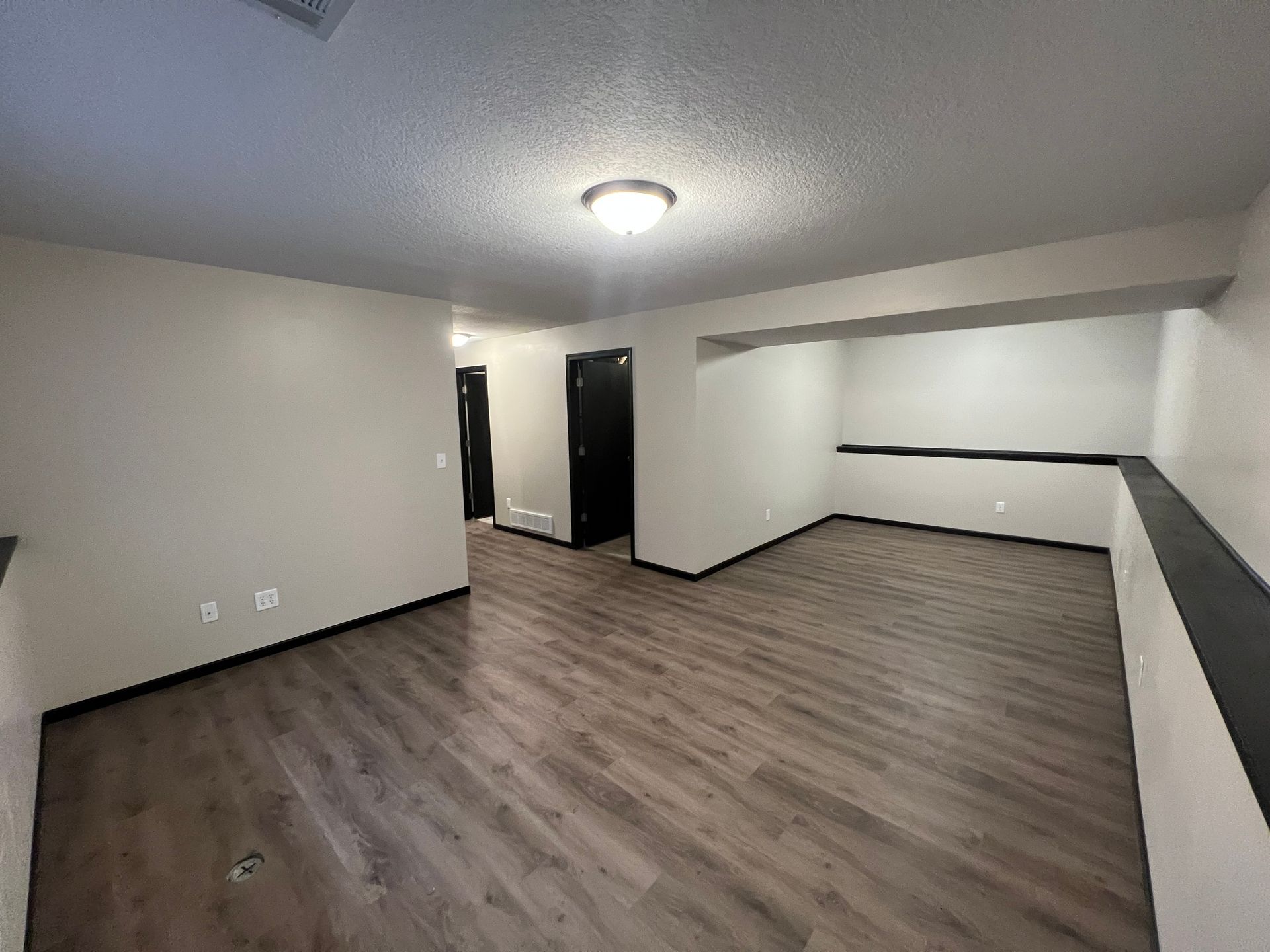 A large empty room with hardwood floors and white walls.