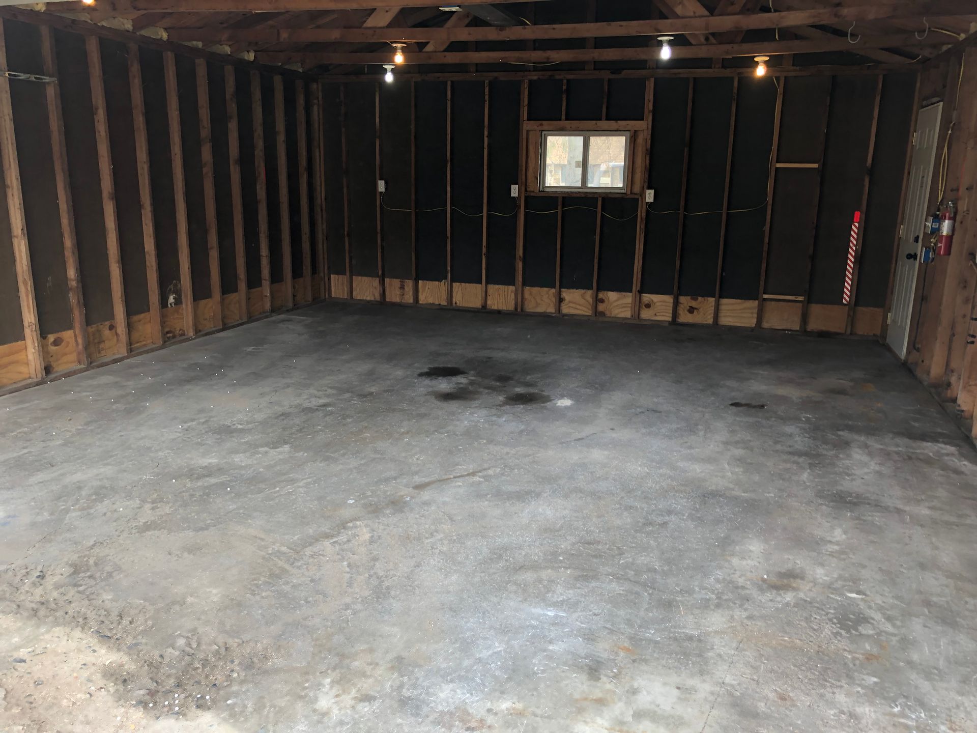 An empty garage with a window and a concrete floor.