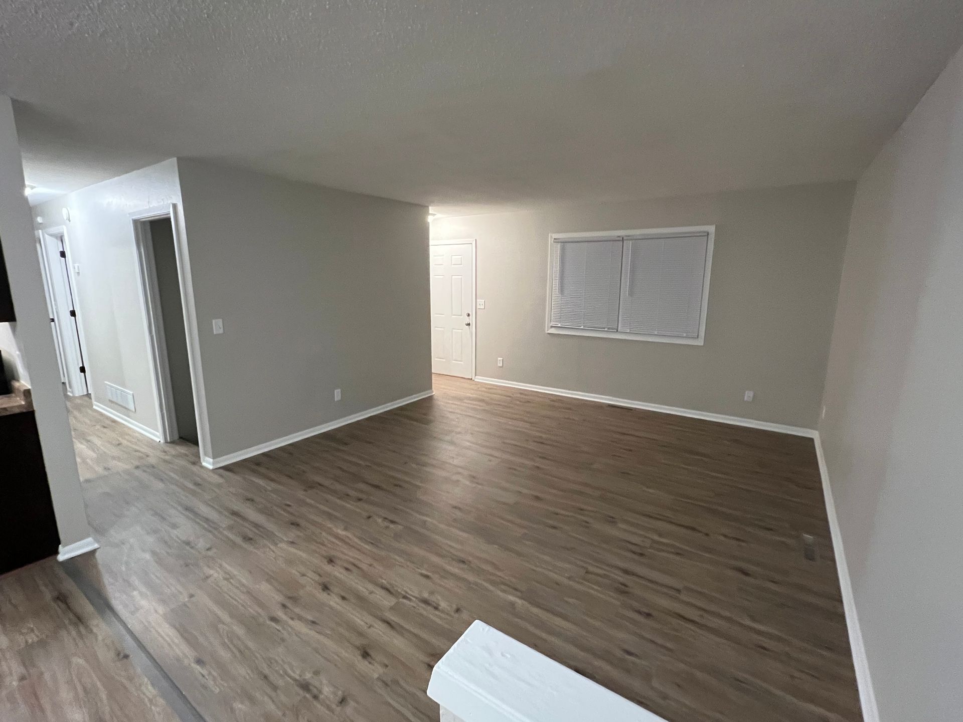 An empty living room with hardwood floors and a window.