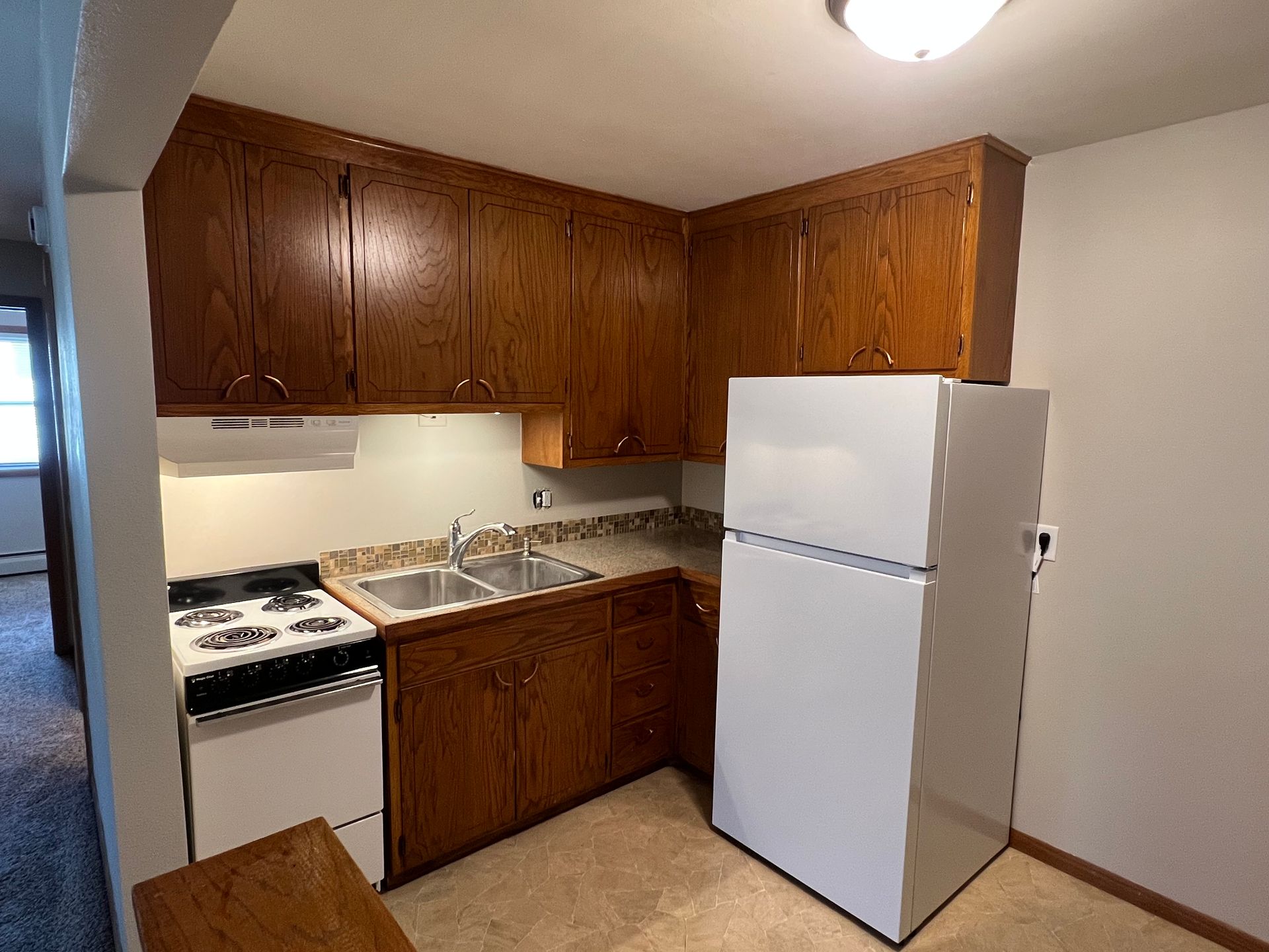 A kitchen with wooden cabinets and a white refrigerator