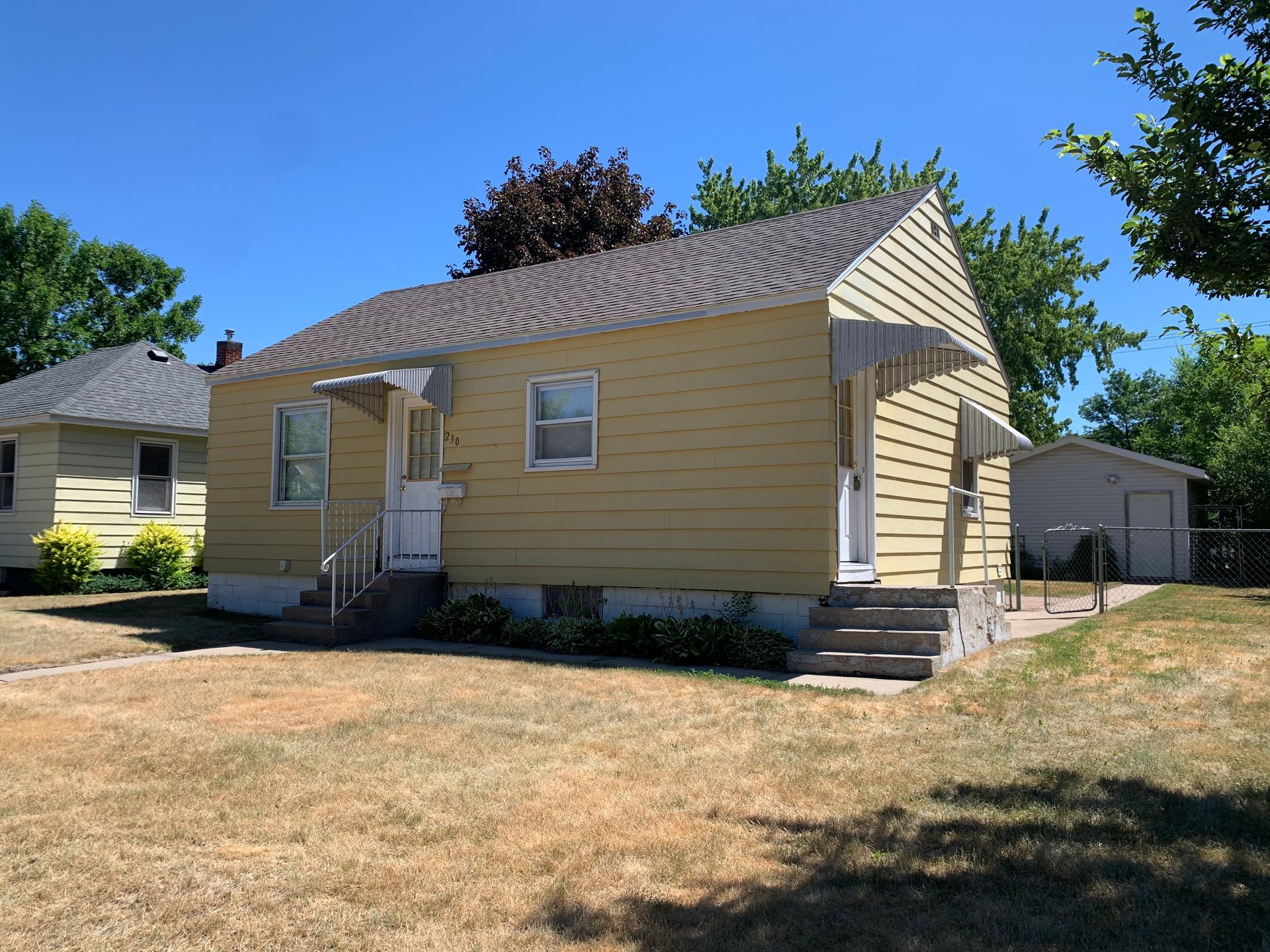 A small yellow house with stairs leading up to the front door