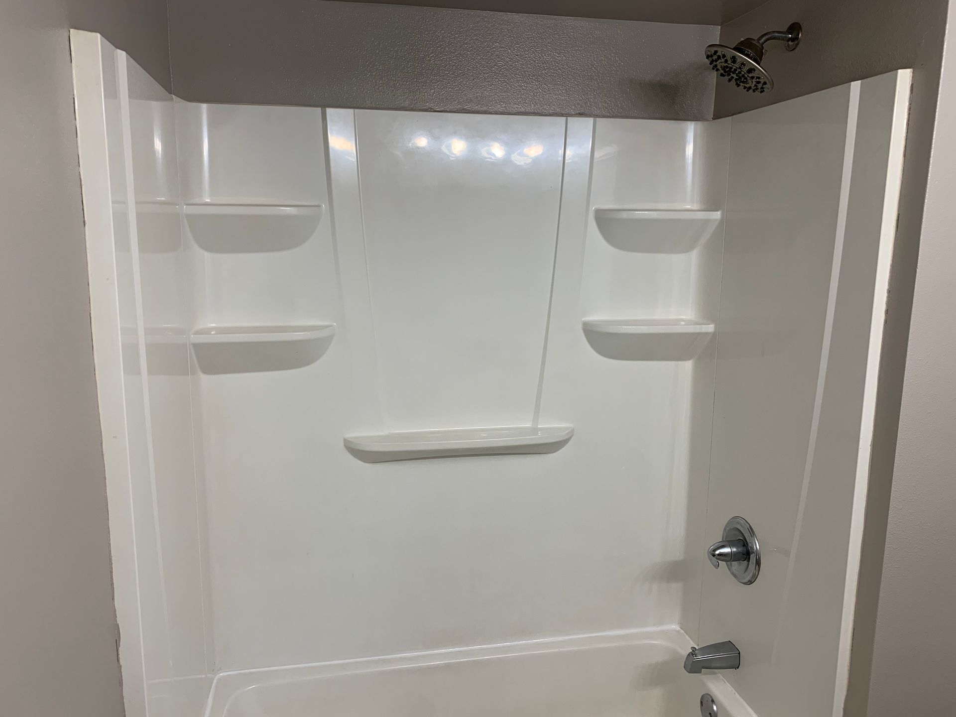 A bathroom with a bathtub , shower , and shelves.