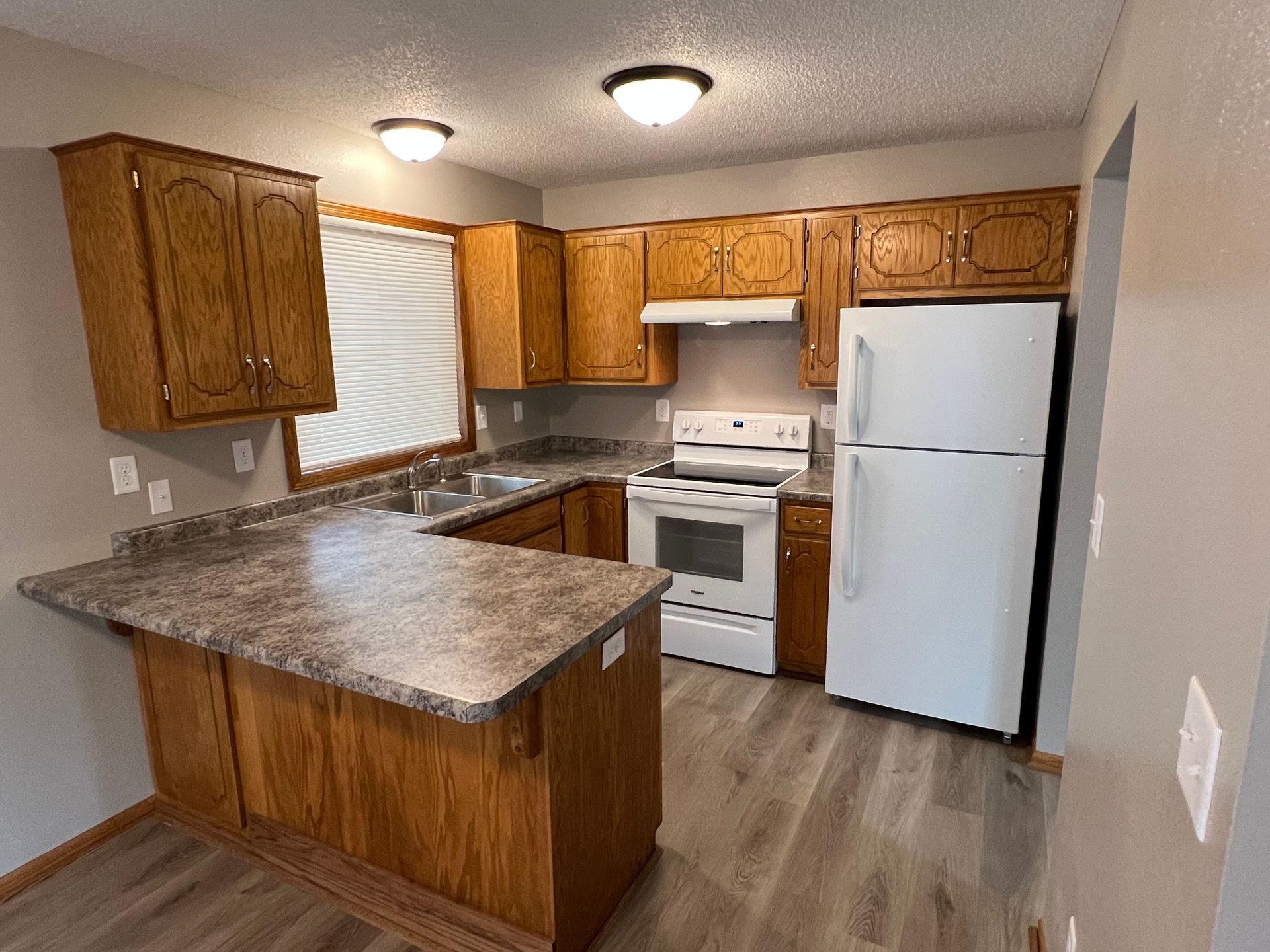 A kitchen with wooden cabinets , a white refrigerator , a stove , and a sink.